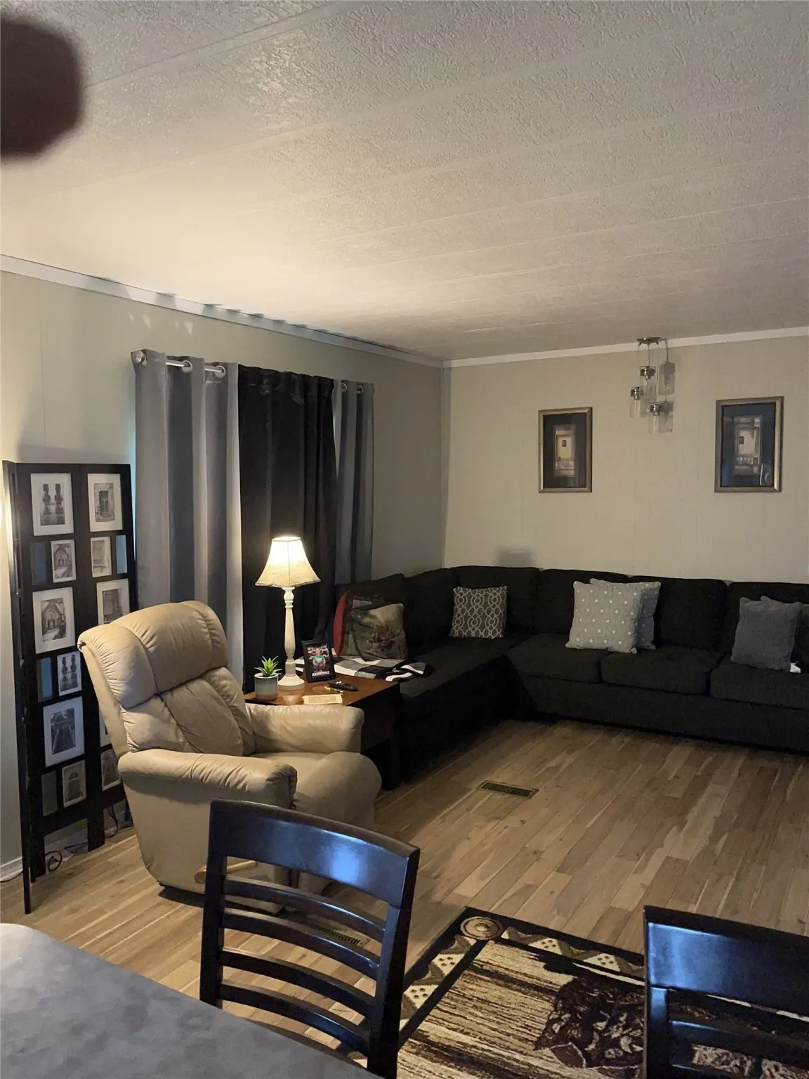 Living room featuring a textured ceiling, light wood finished floors, and ornamental molding