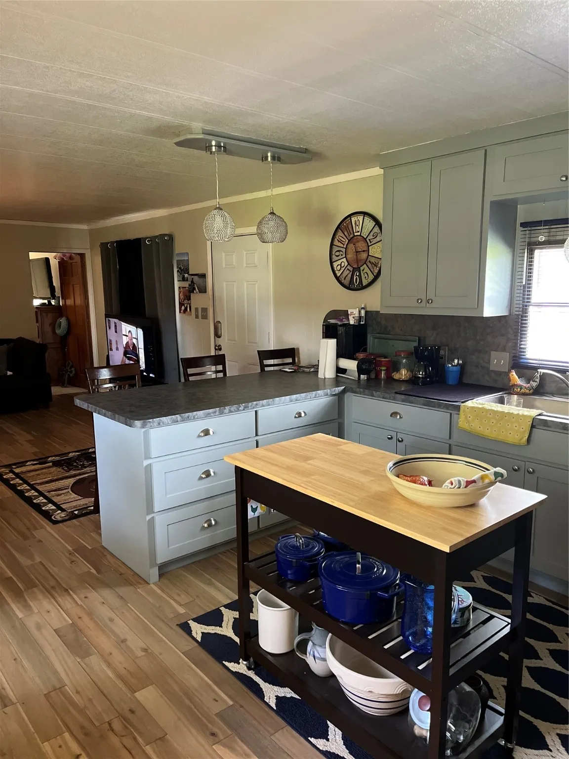 Kitchen featuring a breakfast bar area, dark countertops, light wood-style floors, decorative light fixtures, and crown molding