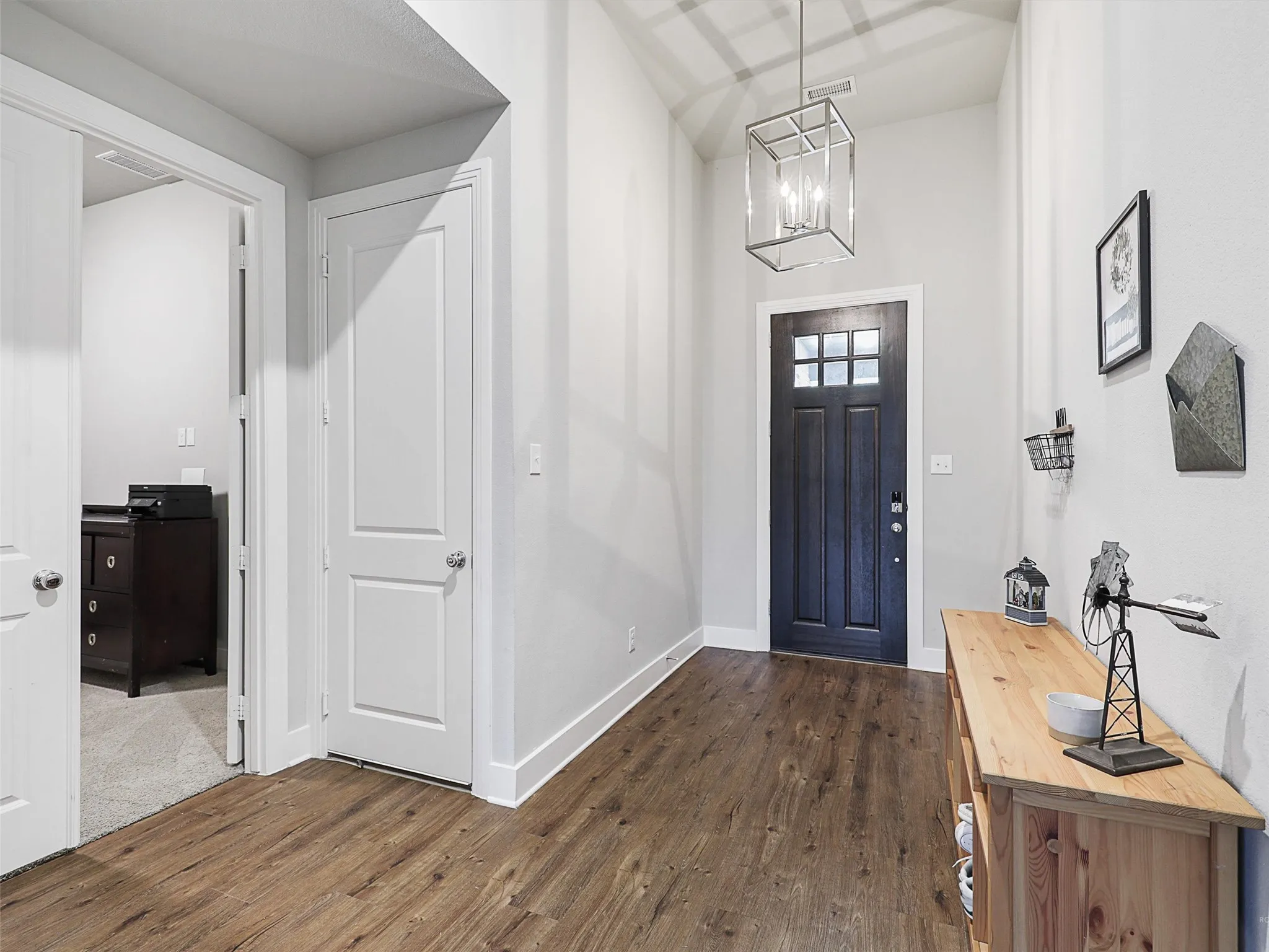 Step inside to a spacious foyer with soaring ceilings, rich wood flooring, and a modern light fixture that sets the tone for this warm, elegant home.