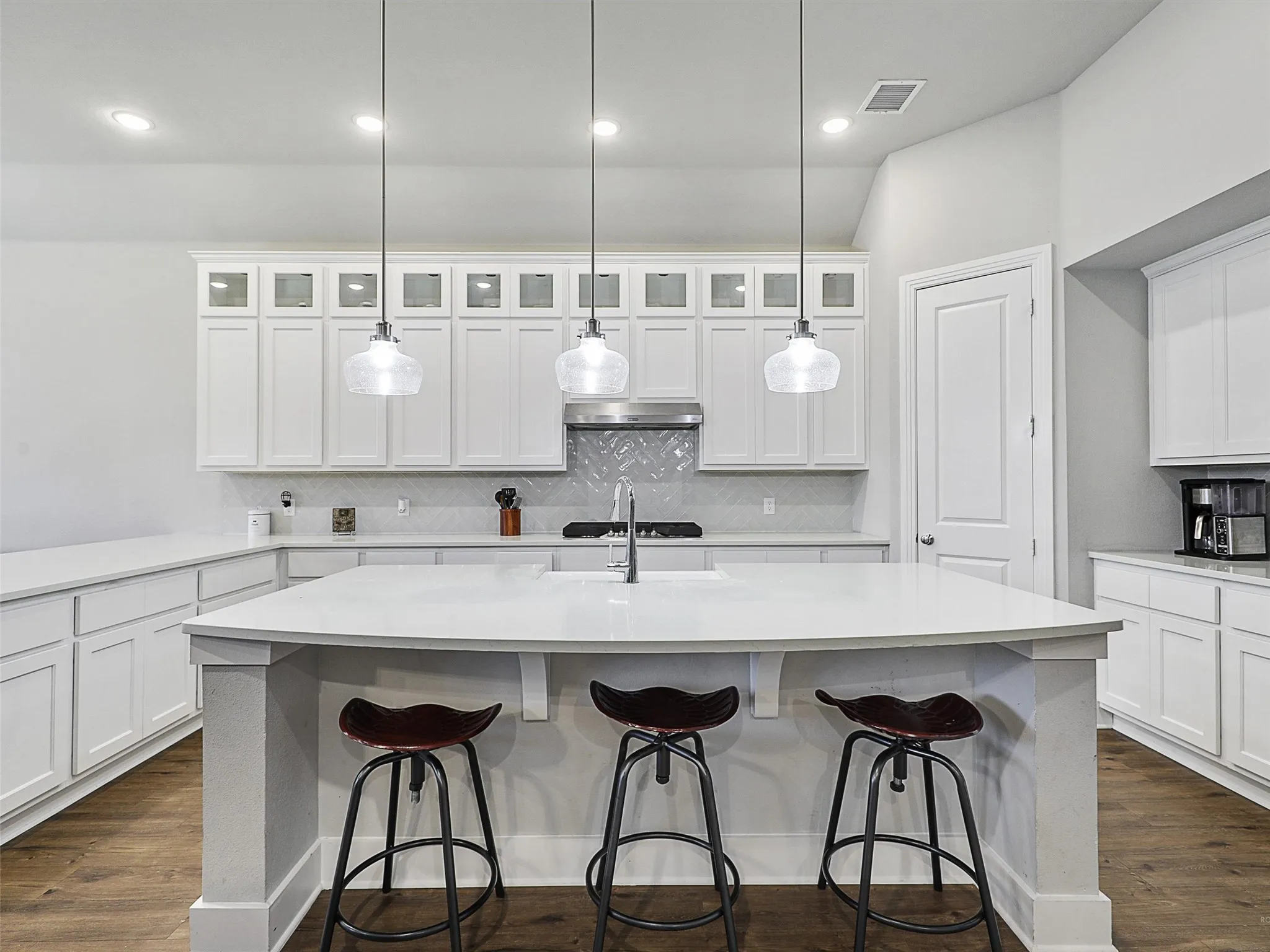 A beautiful blend of form and function, the kitchen boasts a crisp, white palette with a herringbone backsplash and contemporary lighting. The walk-in pantry, gas oven and built-in microwave add convenience for any home cook.