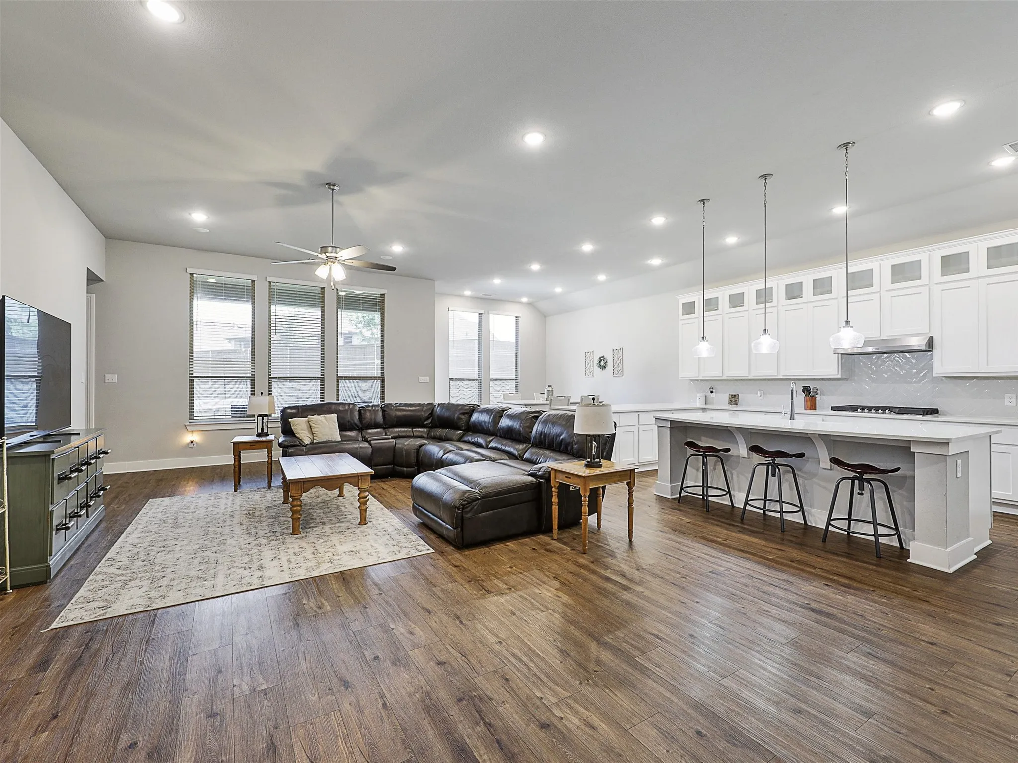 The heart of the home features a large open floor plan with a cozy living area, gas fireplace, and wall of windows that bring in natural light. The seamless flow into the kitchen and dining spaces makes entertaining effortless.