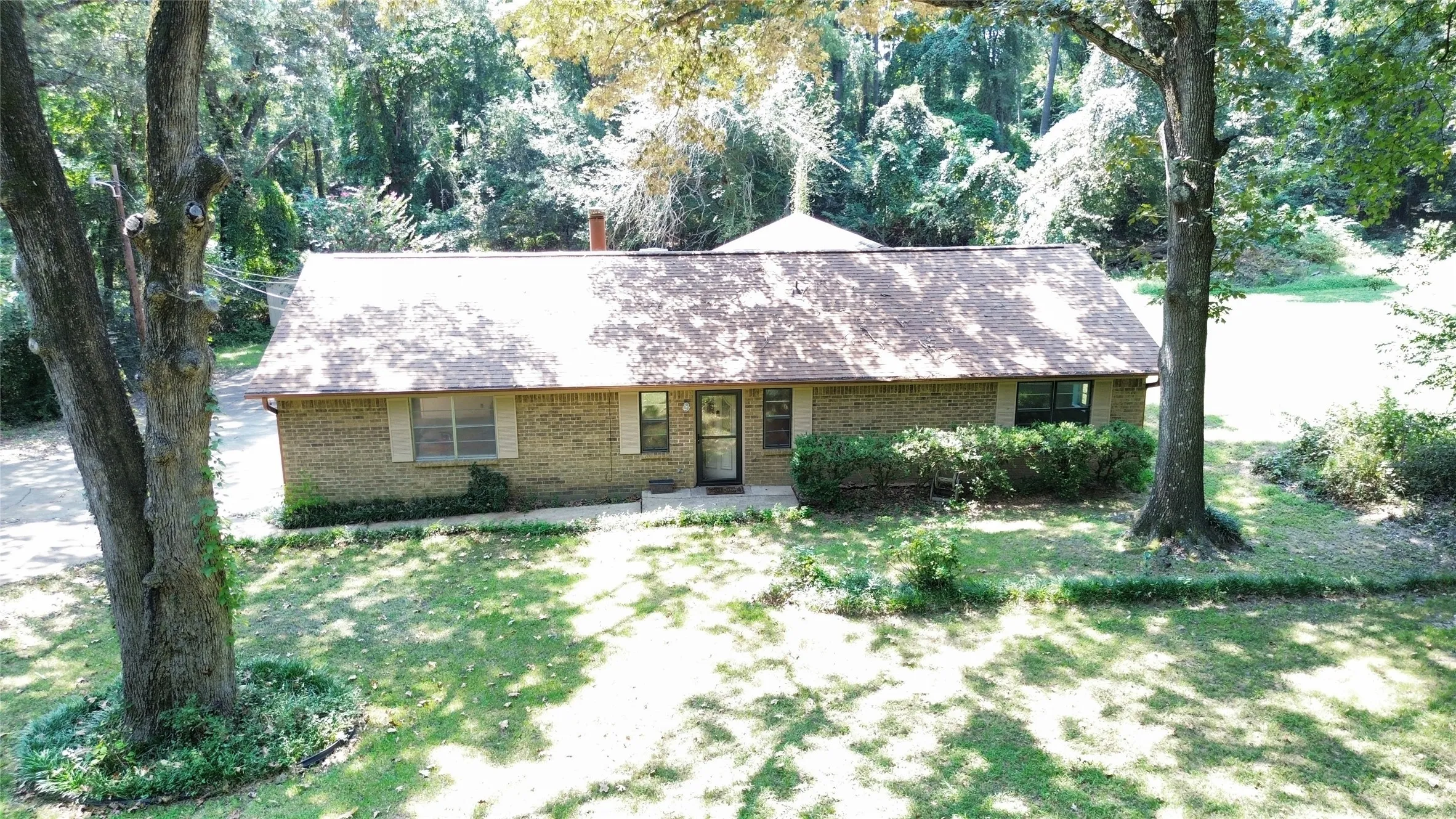 View of front of property with brick siding, a shingled roof, and a front yard