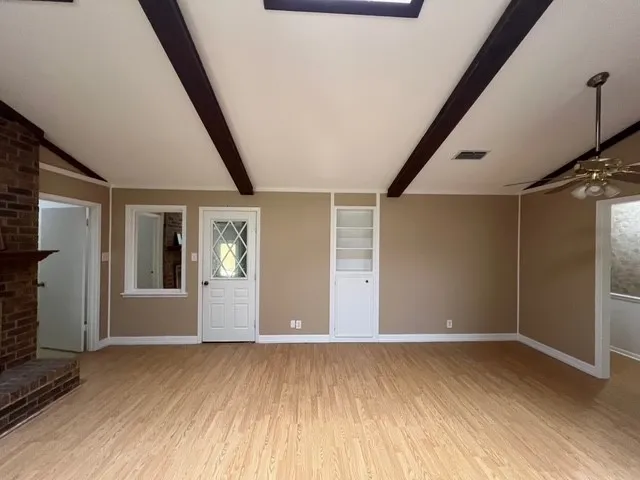 Unfurnished living room featuring light wood-type flooring, ceiling fan, and a brick fireplace