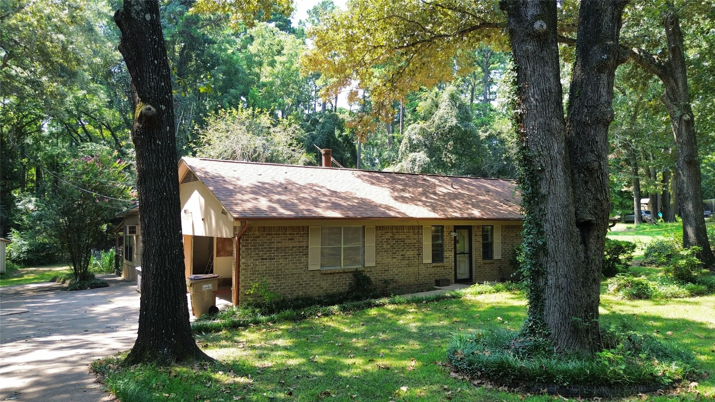 Ranch-style home with brick siding, a front lawn, a shingled roof, and concrete driveway
