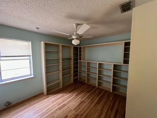 Unfurnished bedroom with light wood-type flooring, a textured ceiling, a ceiling fan, and a closet