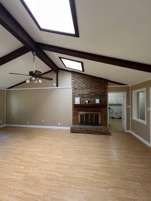 Unfurnished living room with a fireplace, light wood-style flooring, and ceiling fan