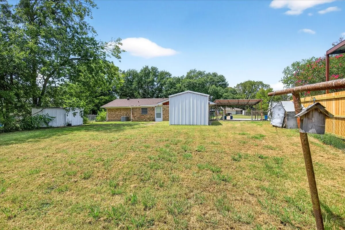 View of green lawn with a carport and a shed