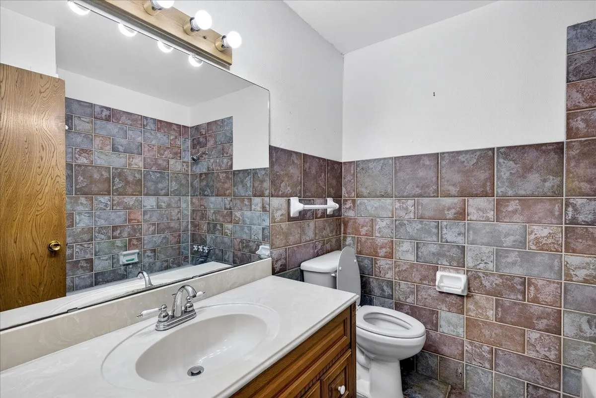 Full bath with vanity, tile walls, and a wainscoted wall