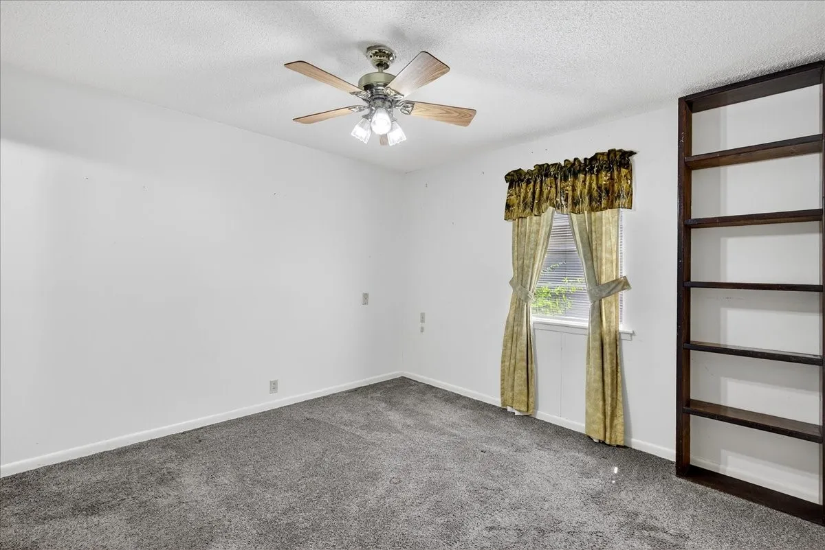 Carpeted empty room featuring a textured ceiling and a ceiling fan