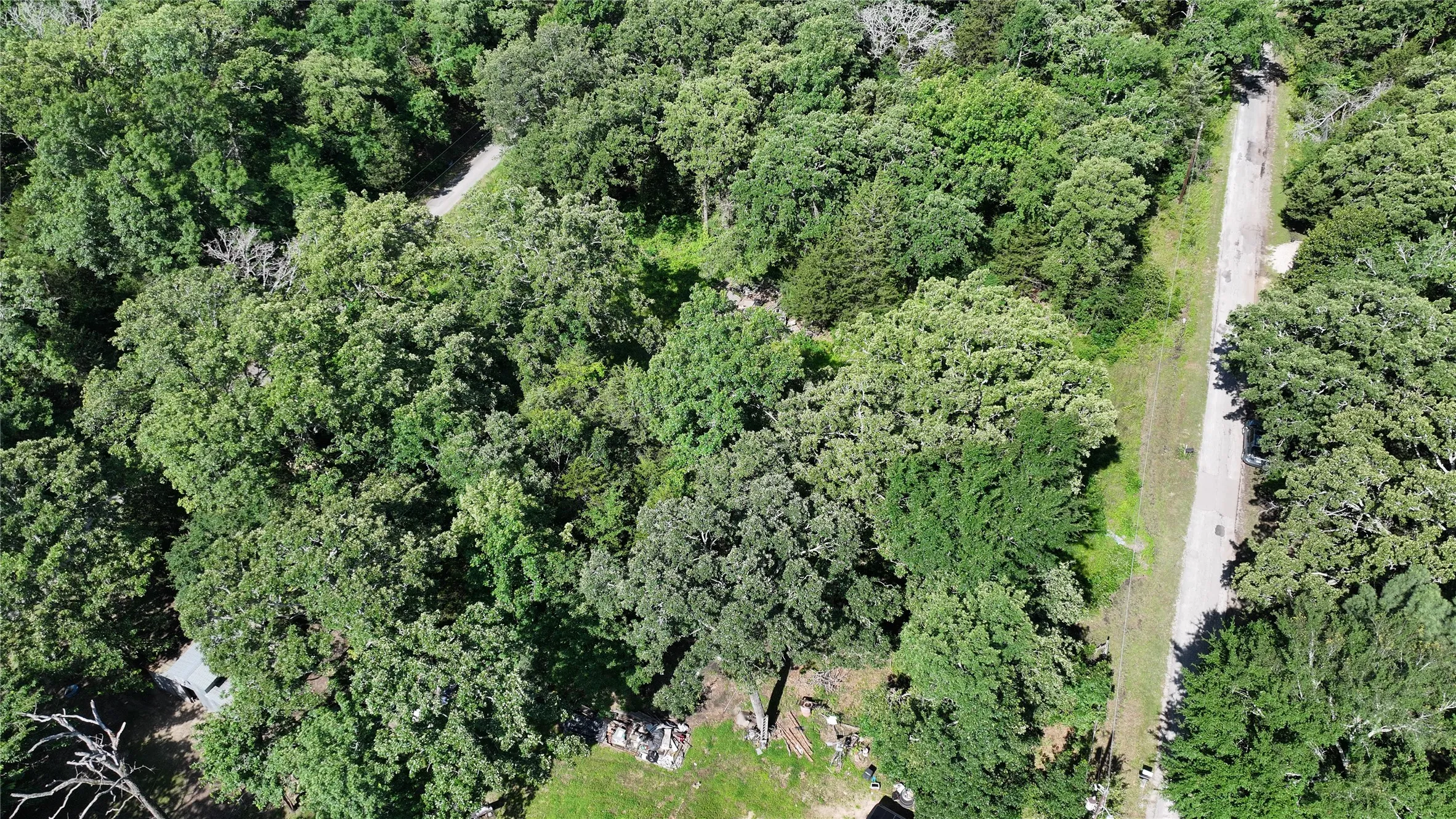 Aerial view of property and surrounding area featuring a forest
