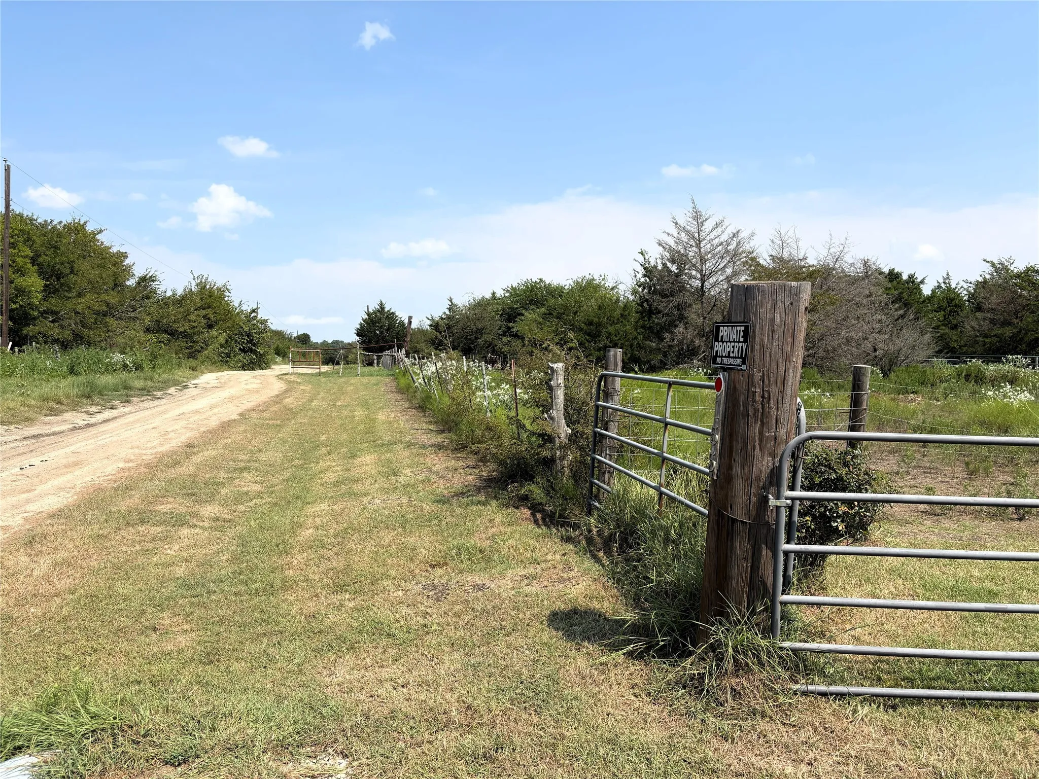 View of dirt / gravel road with a gate, a view of rural / pastoral area, and a gated entry
