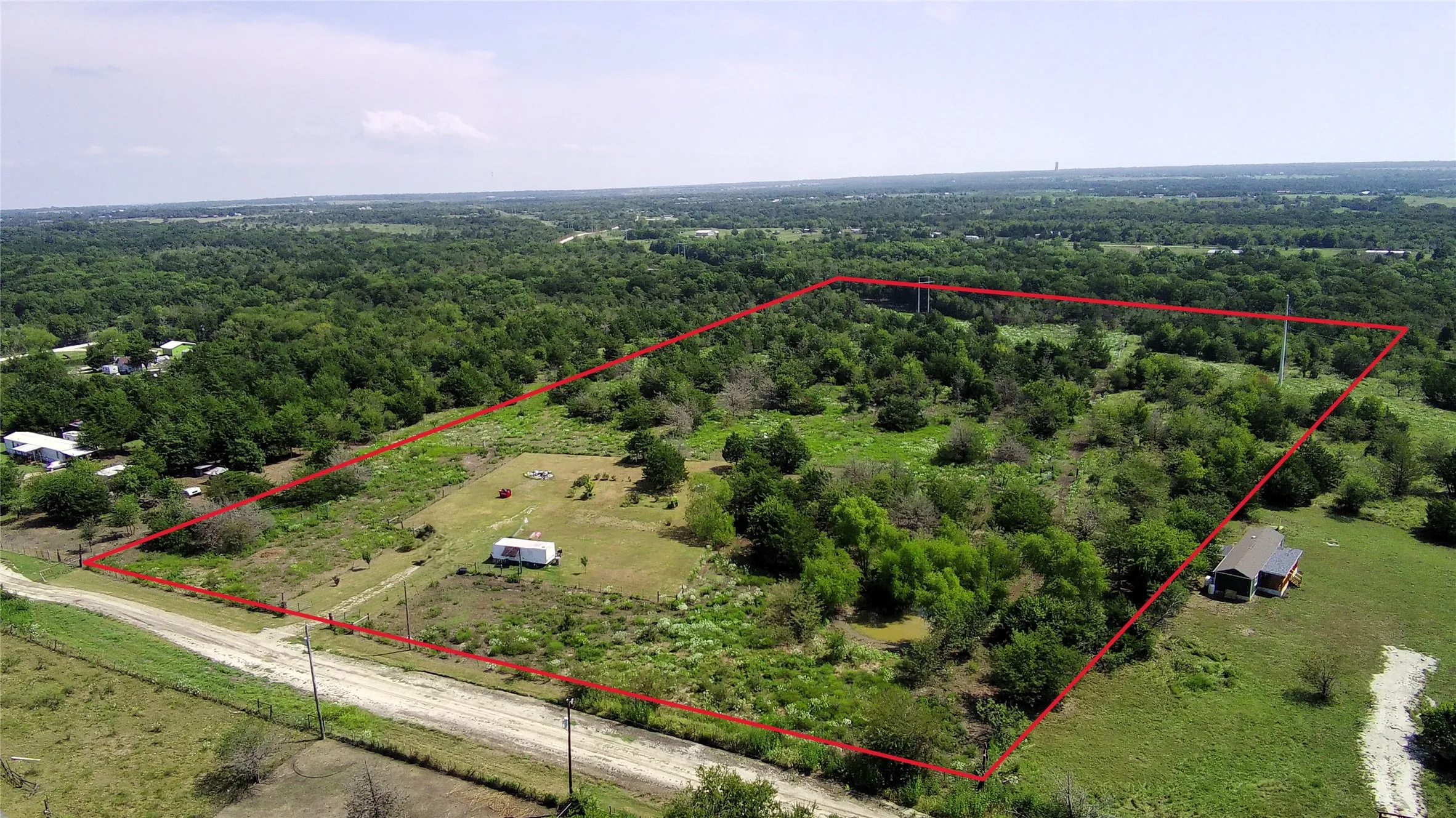 View of rural area featuring property parcel outlined and a forest