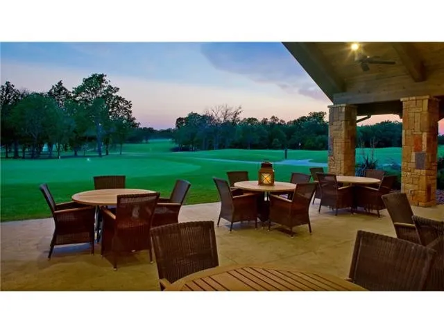 Patio terrace at dusk featuring outdoor dining space, view of golf course, a patio, and a lawn