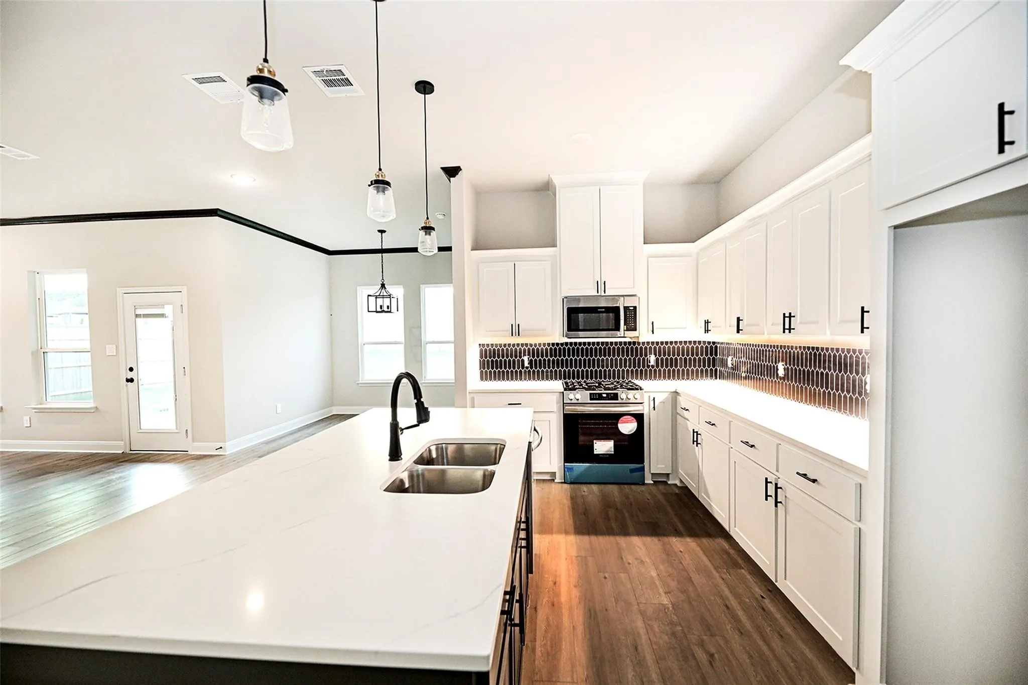 Kitchen with dark hardwood / wood-style floors, sink, white cabinetry, gas range oven, and light stone counters