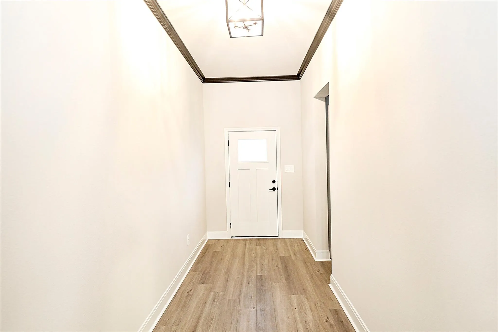 Doorway to outside featuring crown molding and light hardwood / wood-style floors