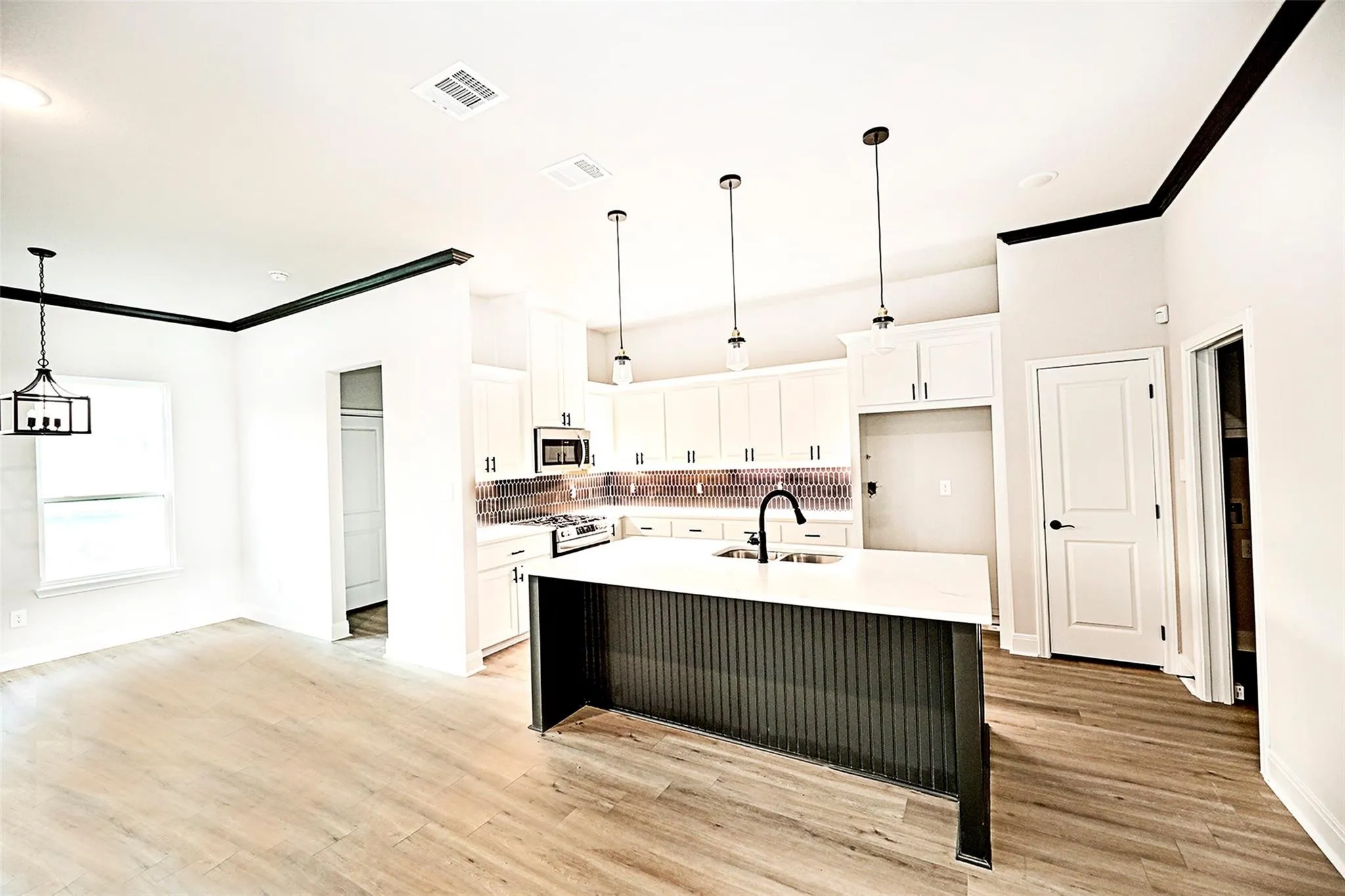 Kitchen with white electric stove, an island with sink, sink, white cabinetry, and light hardwood / wood-style flooring