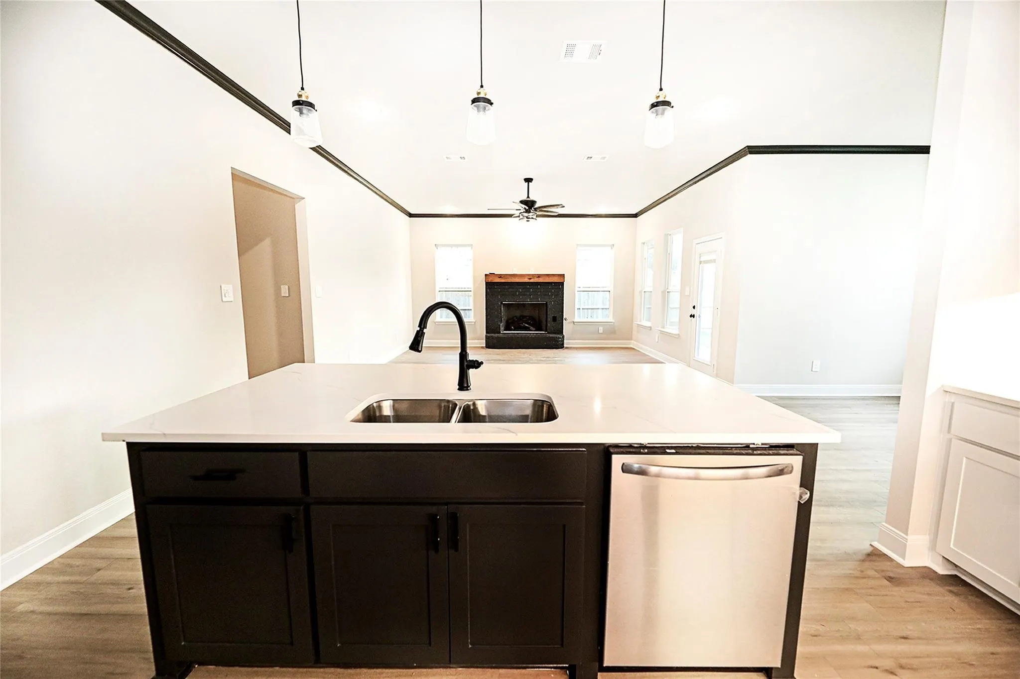 Kitchen featuring light wood-type flooring, a kitchen island with sink, dishwasher, ceiling fan, and sink