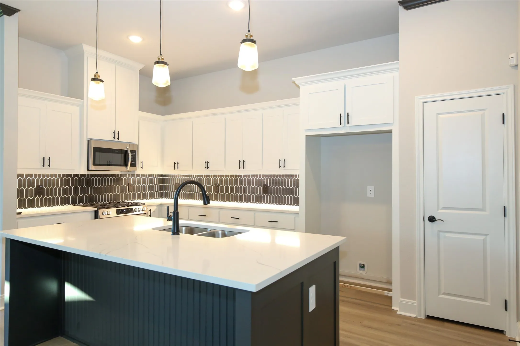 Kitchen with white cabinets, sink, an island with sink, and pendant lighting