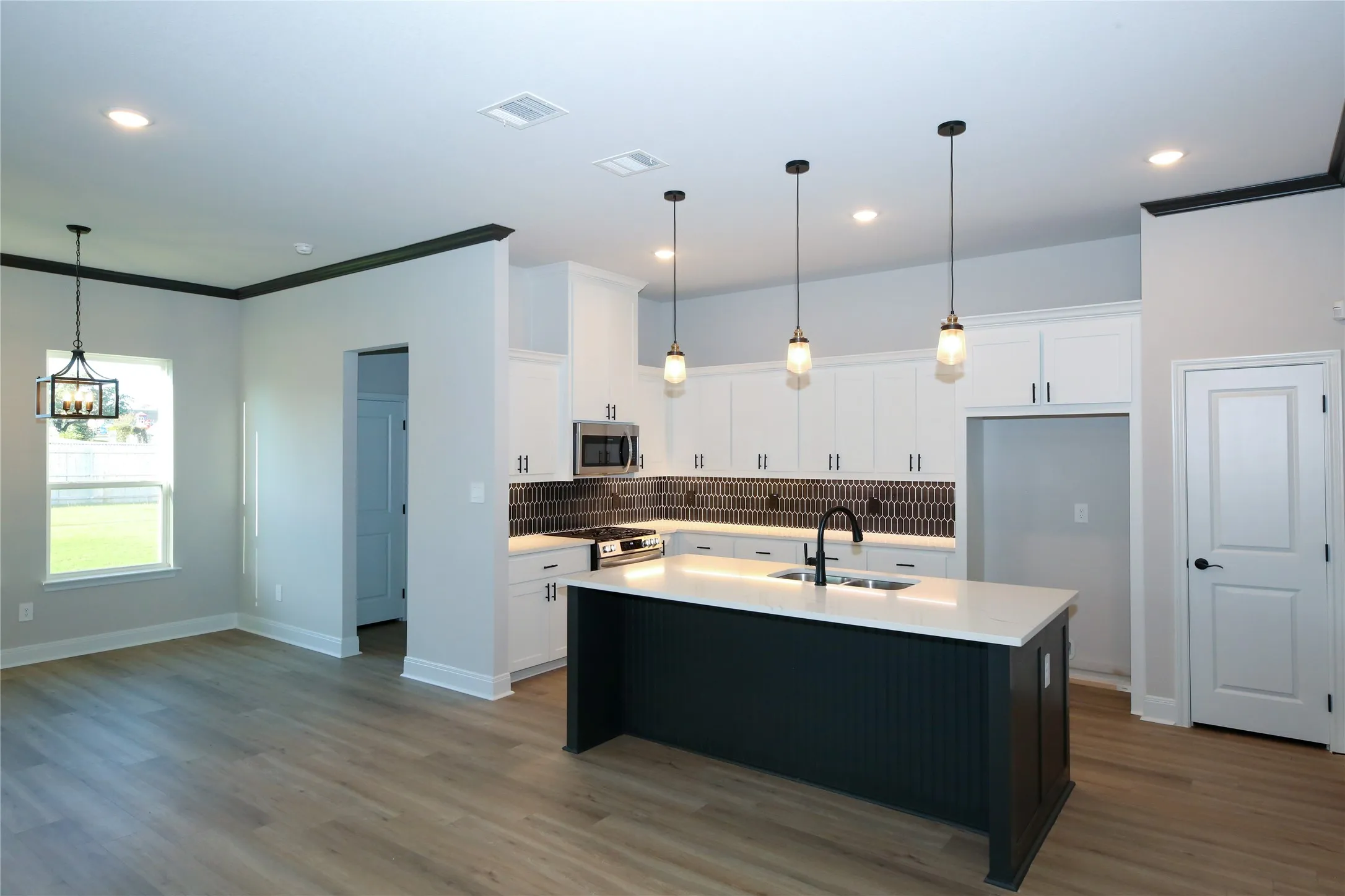 Kitchen featuring white cabinets, appliances with stainless steel finishes, a kitchen island with sink, and hardwood / wood-style floors