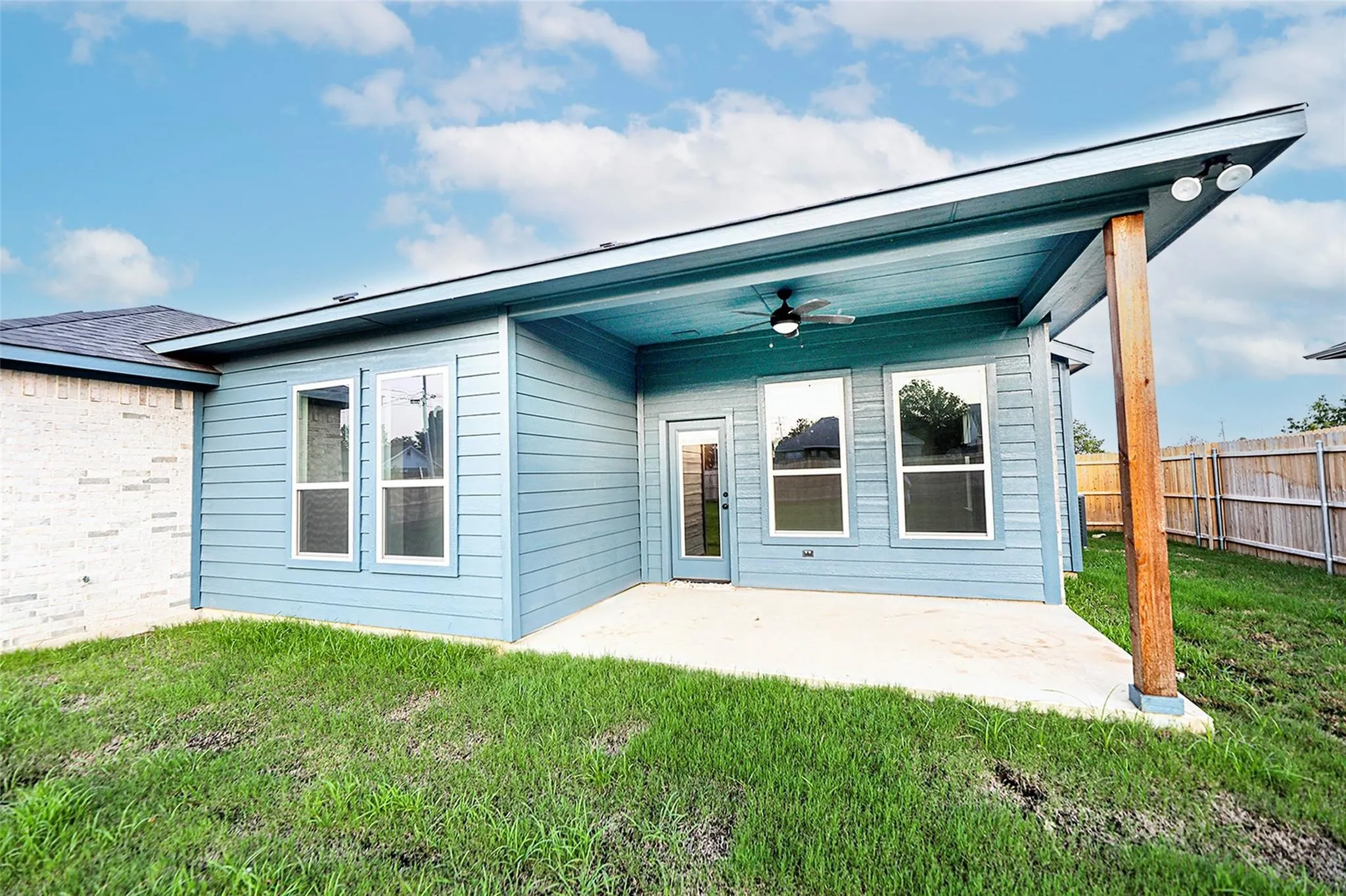 Back of property featuring ceiling fan, a patio area, and a yard