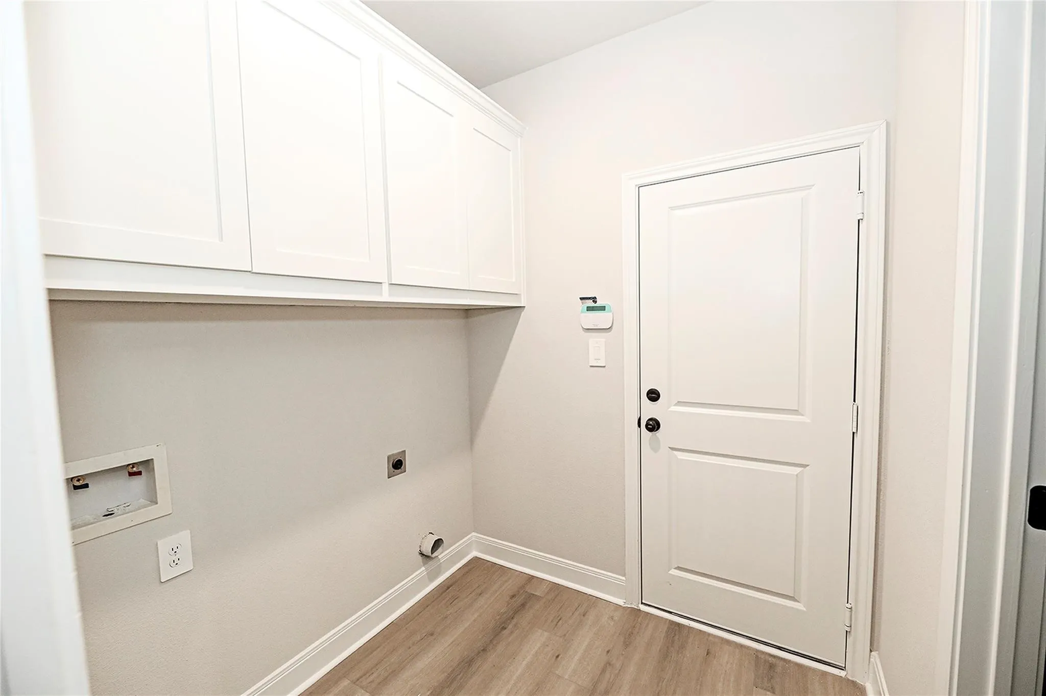 Washroom with cabinets, light wood-type flooring, hookup for an electric dryer, and washer hookup