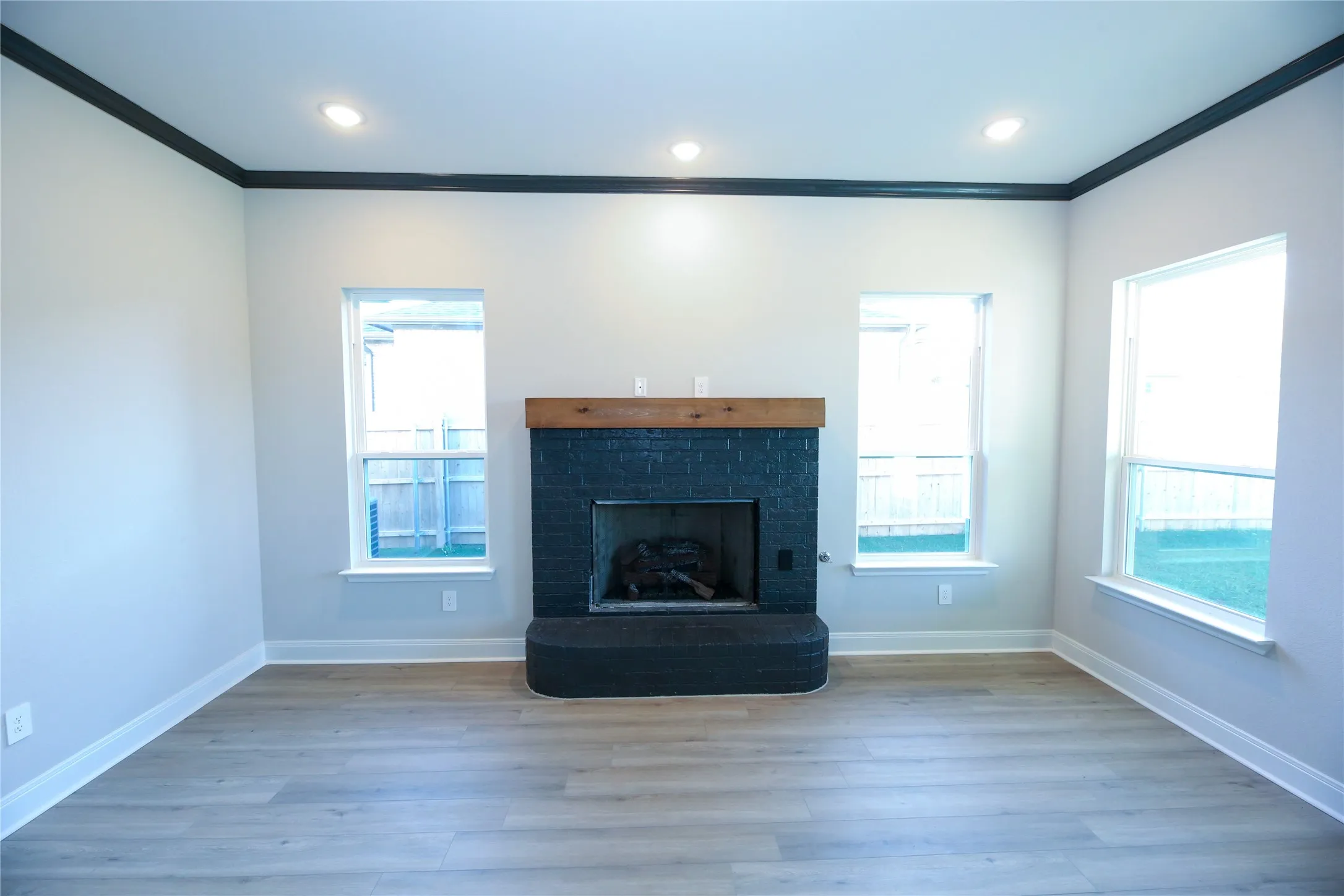 Unfurnished living room with a brick fireplace, ornamental molding, and light hardwood / wood-style flooring