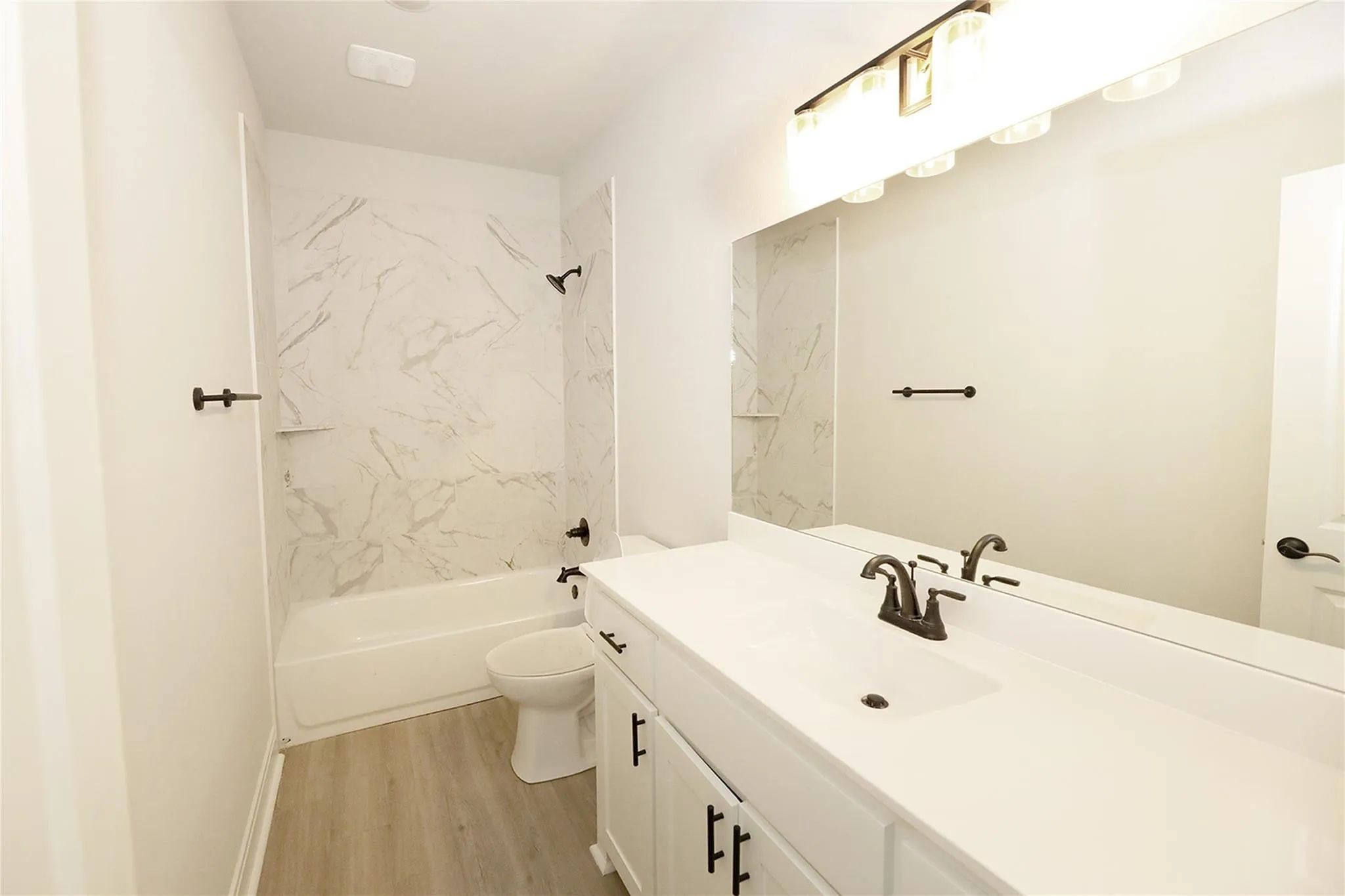 Full bathroom with toilet, vanity, hardwood / wood-style flooring, and tiled shower / bath
