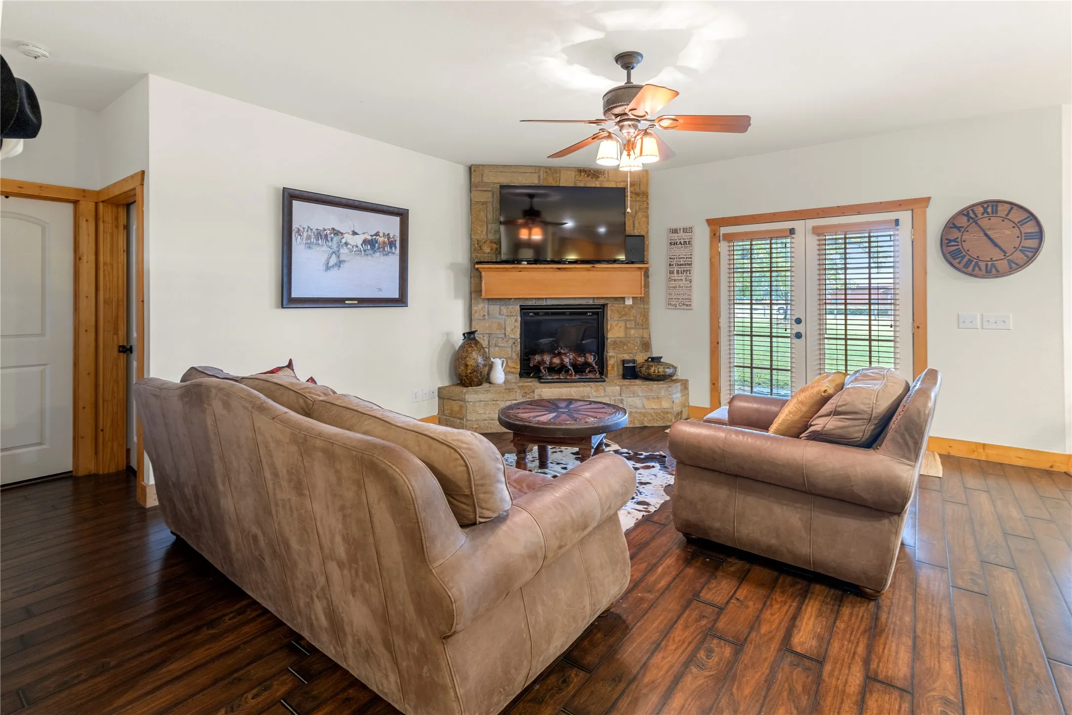Living area featuring dark wood-style floors, a fireplace, and a ceiling fan