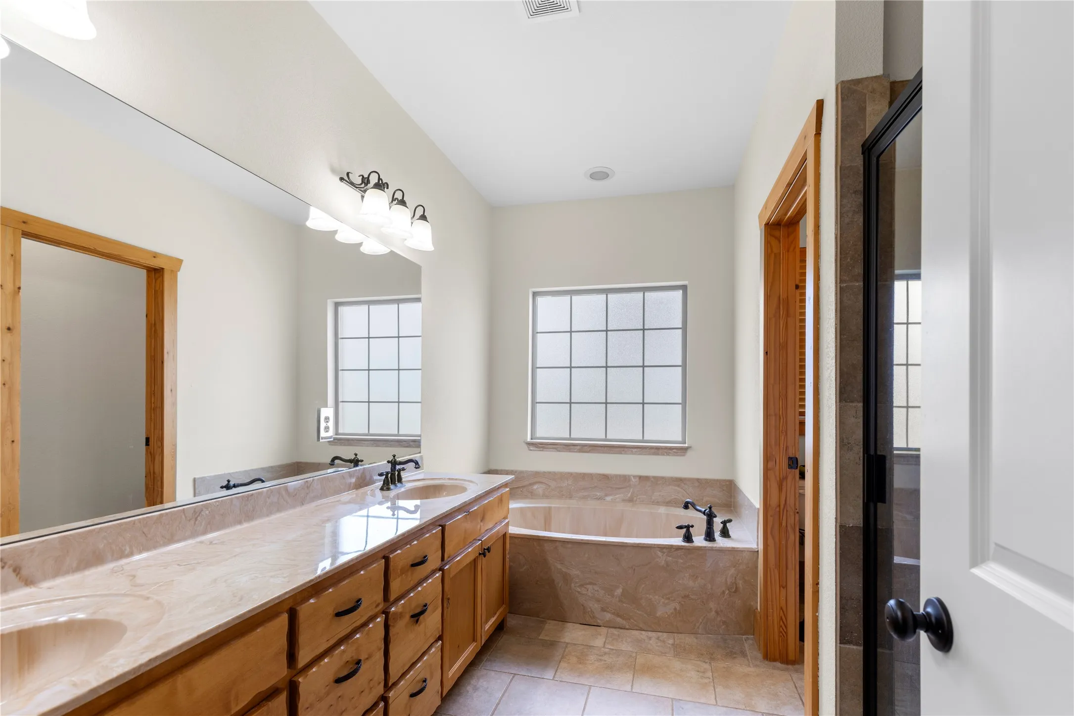 Full bathroom with double vanity, a bath, and light tile patterned flooring