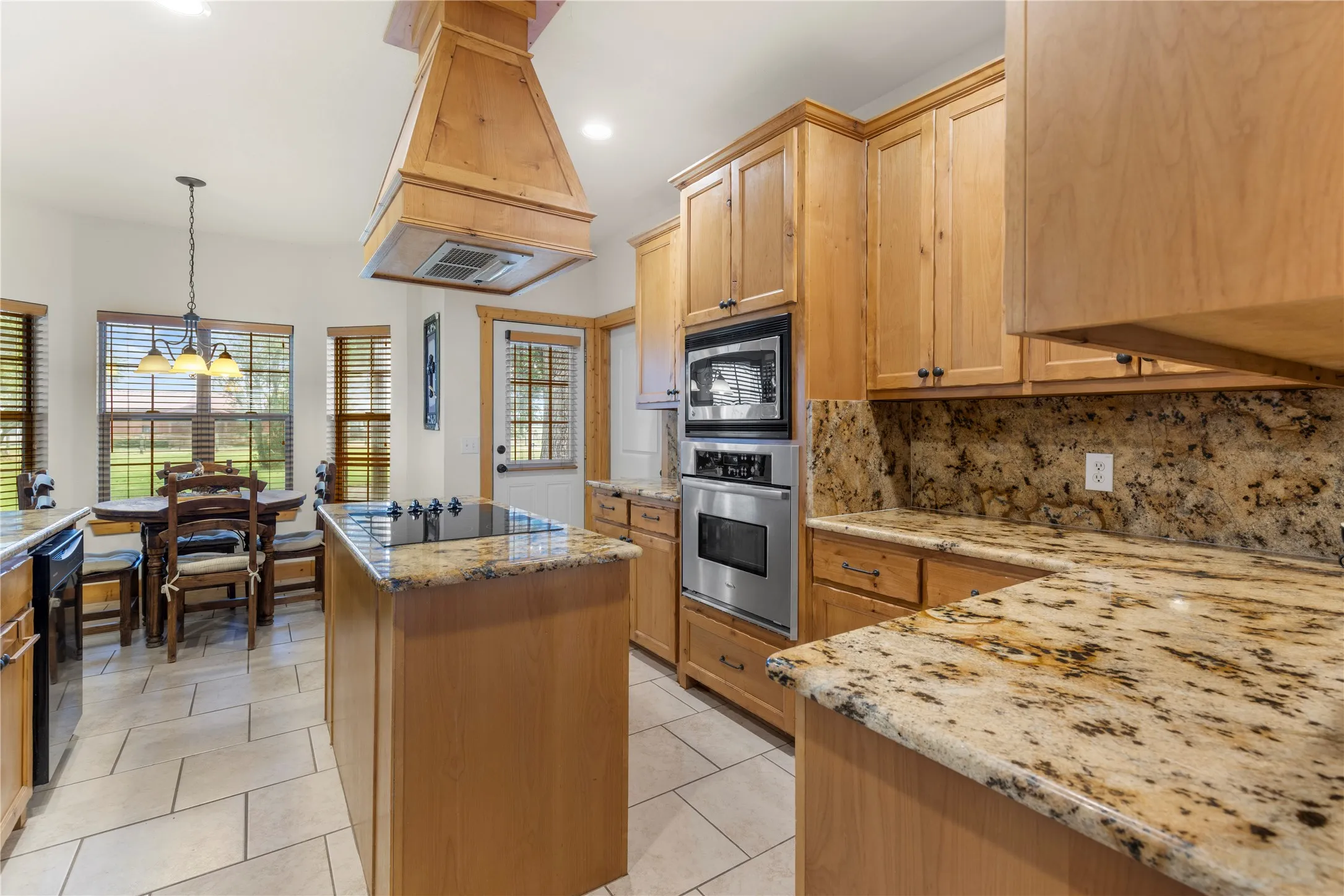 Kitchen with backsplash, a kitchen island, pendant lighting, recessed lighting, and black appliances
