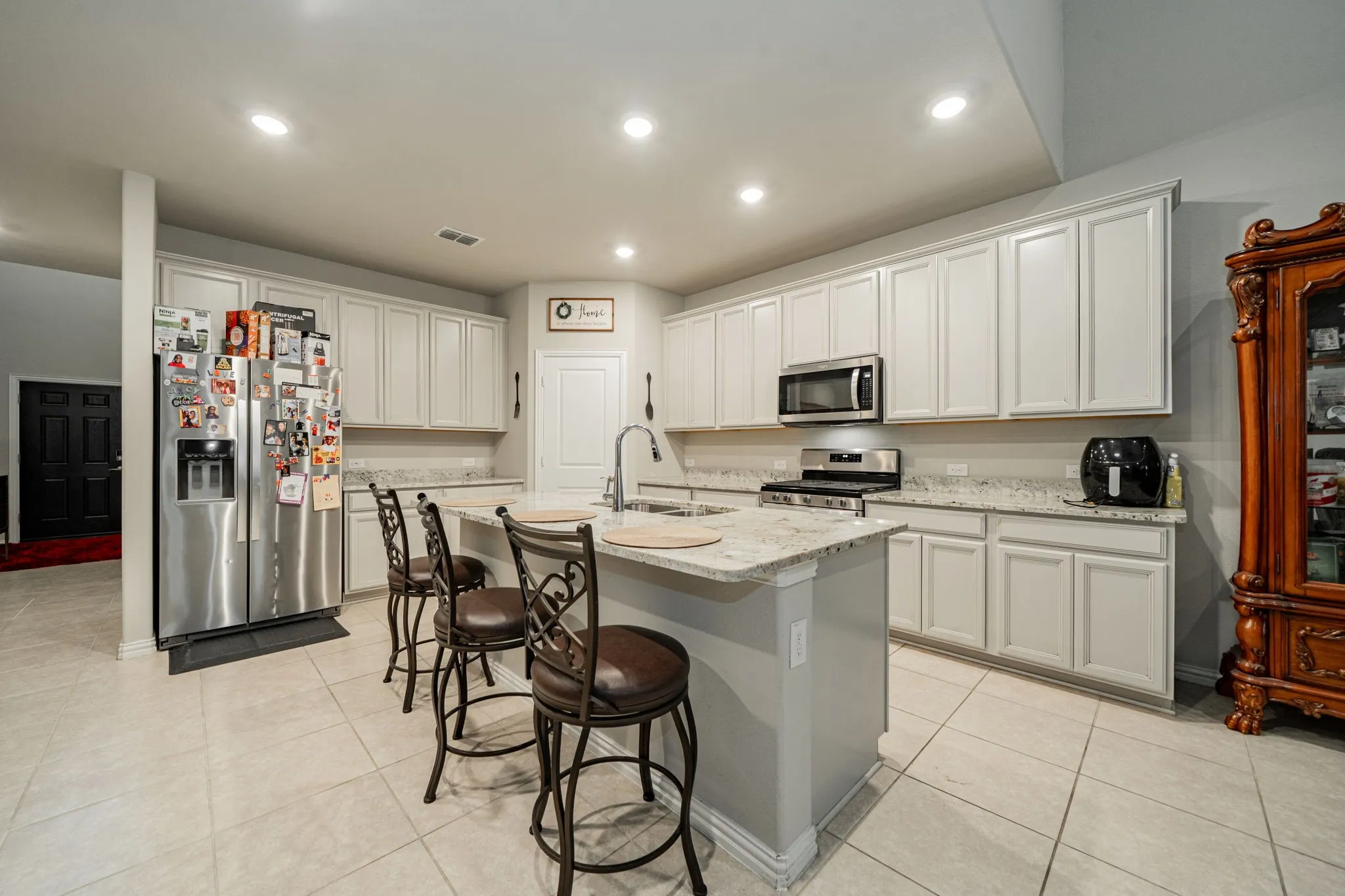 Kitchen featuring light stone countertops, appliances with stainless steel finishes, a breakfast bar, recessed lighting, and light tile patterned flooring