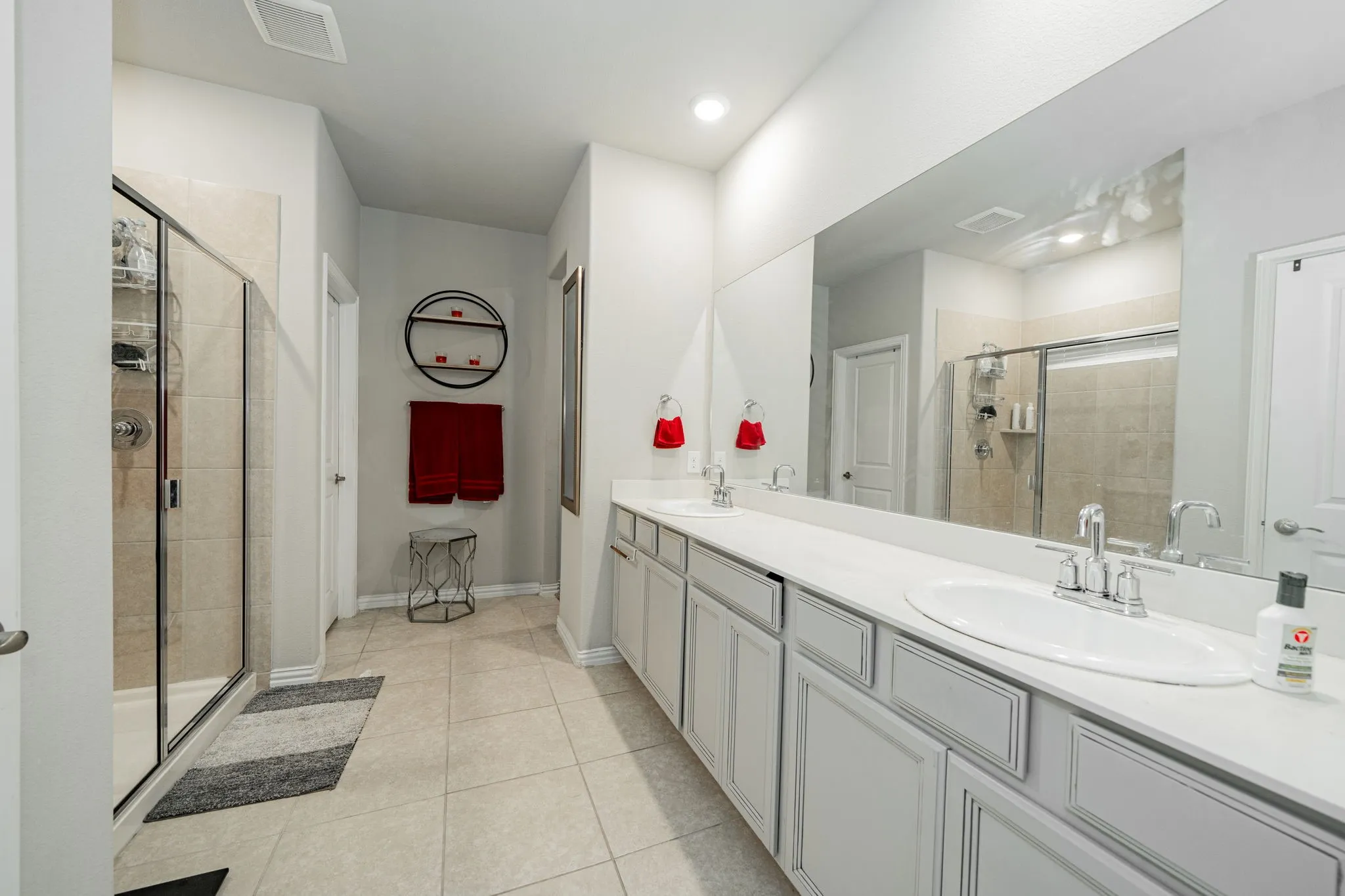 Bathroom featuring a stall shower, double vanity, light tile patterned flooring, and recessed lighting