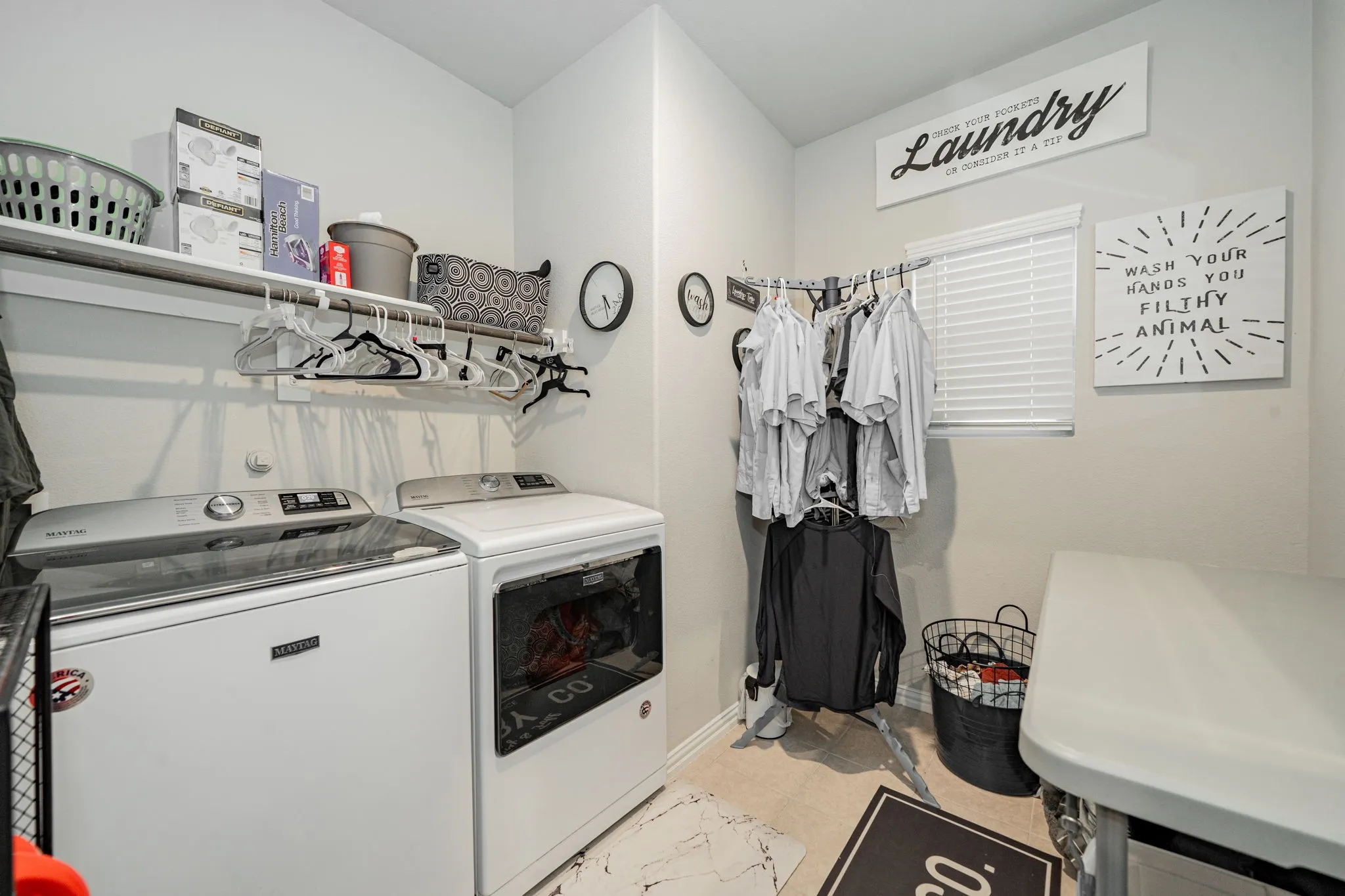 Washroom with washing machine and clothes dryer and light tile patterned floors