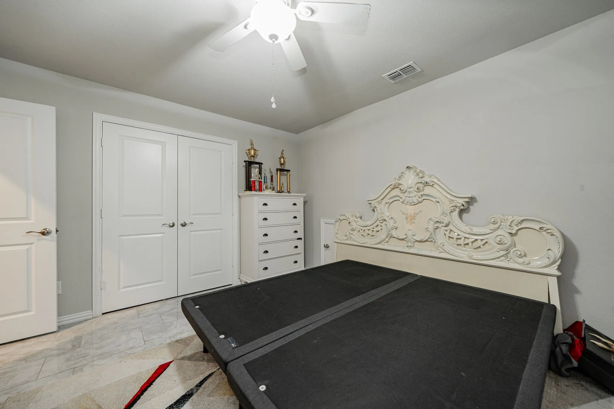 Bedroom featuring ceiling fan, a closet, and light stone finish flooring