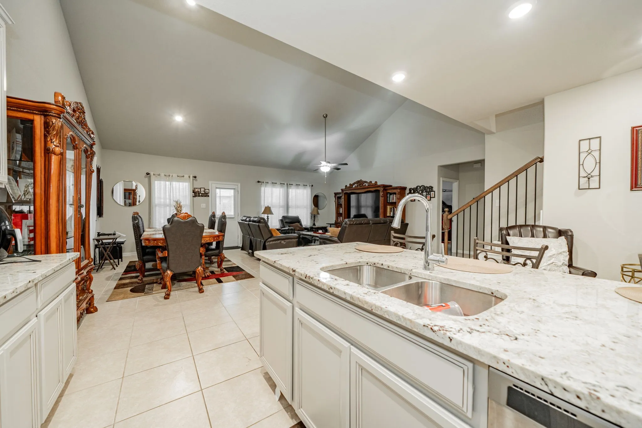 Kitchen featuring light stone counters, white cabinets, ceiling fan, light tile patterned flooring, and dishwasher