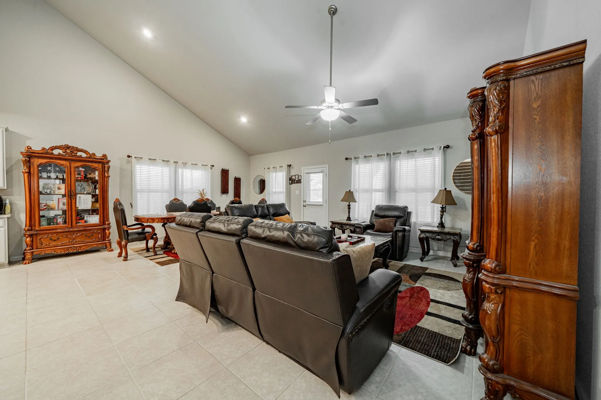 Living area featuring high vaulted ceiling, light tile patterned floors, ceiling fan, and recessed lighting