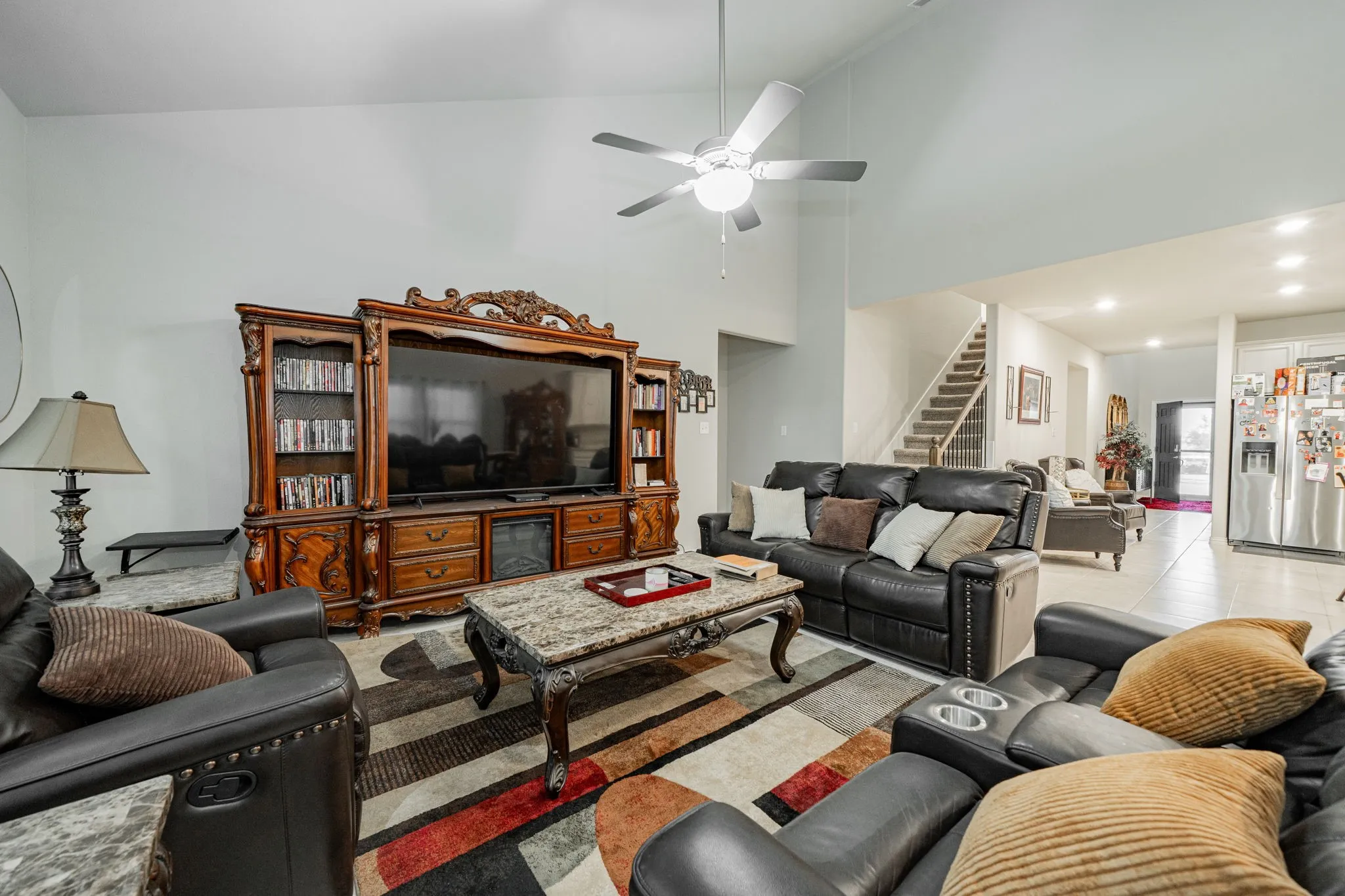 Tiled living area featuring high vaulted ceiling, stairway, and a ceiling fan