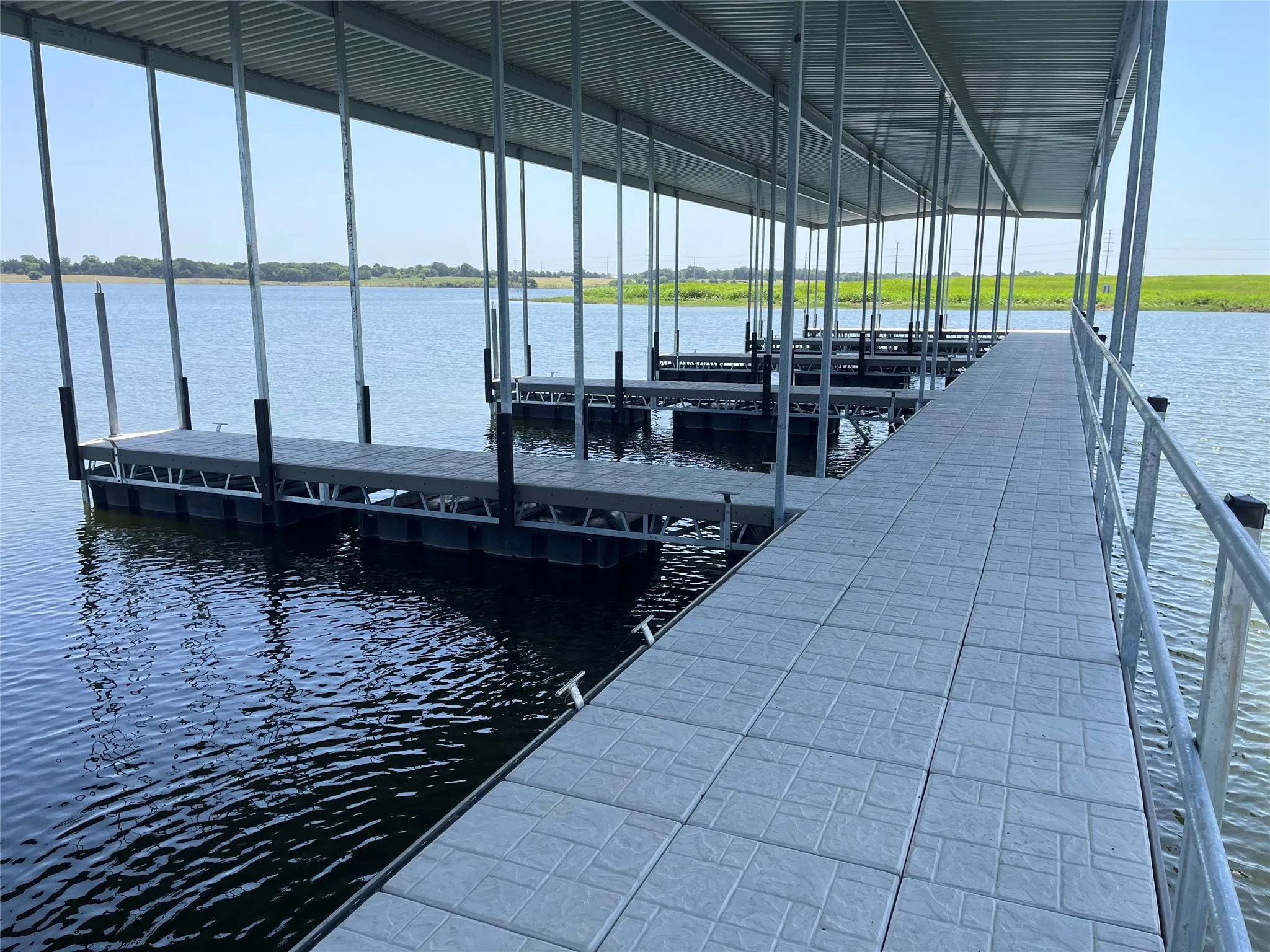 Covered boat dock featuring multiple slips, a wide walkway with textured surfacing, and a steel frame construction