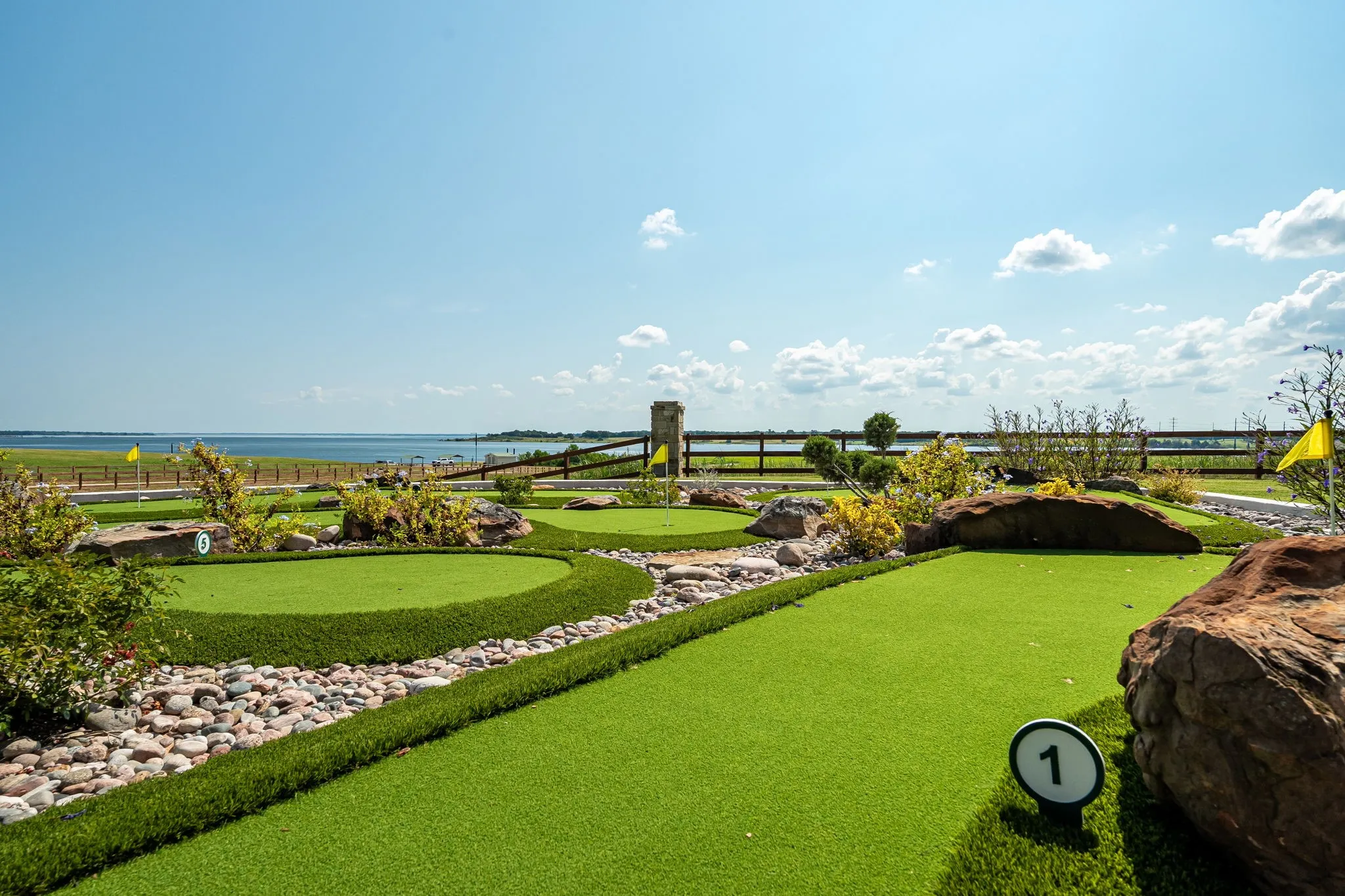 View of property's community with a water view and an area to practice putting