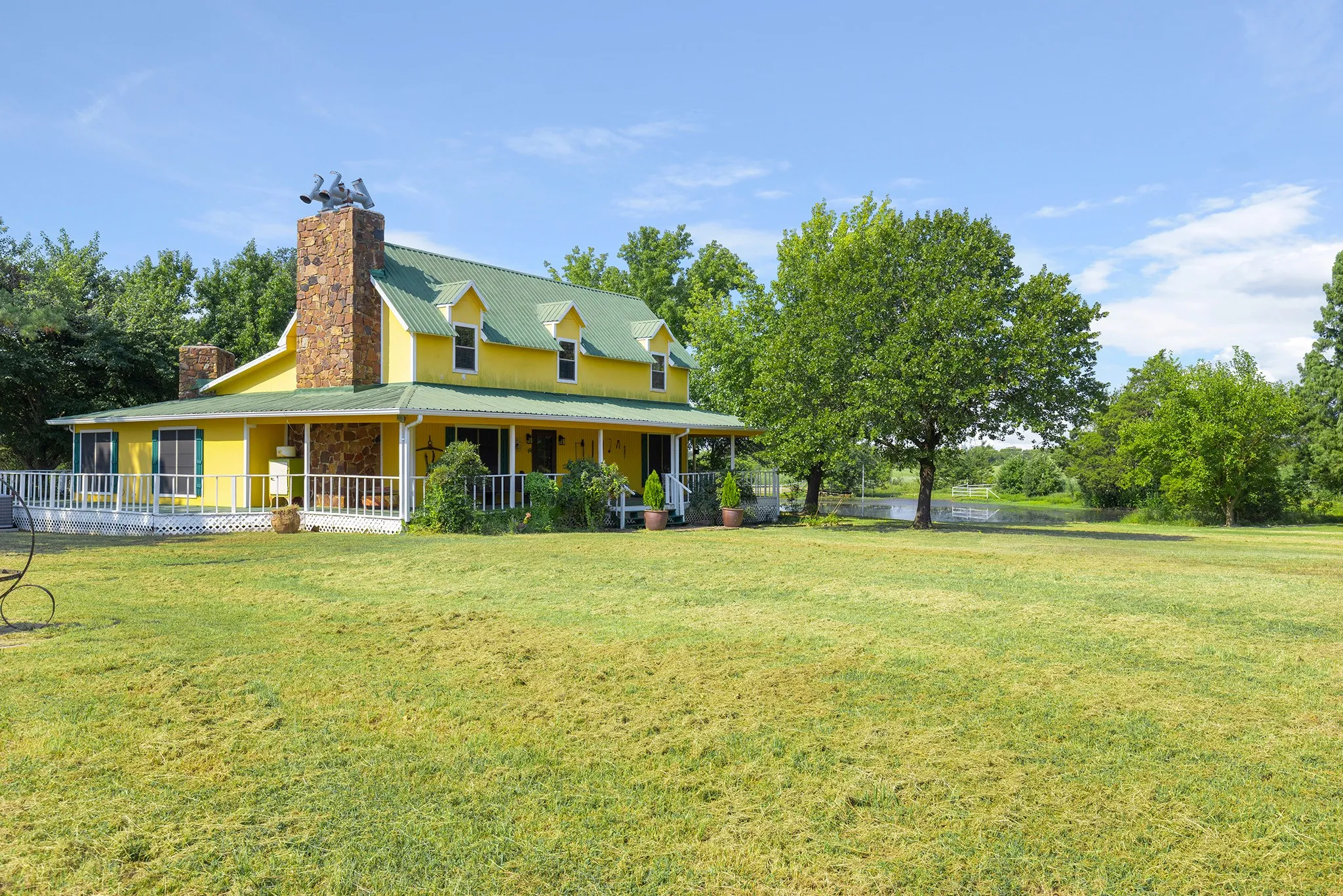 View of front of house with covered porch, a chimney, a metal roof, and a front lawn