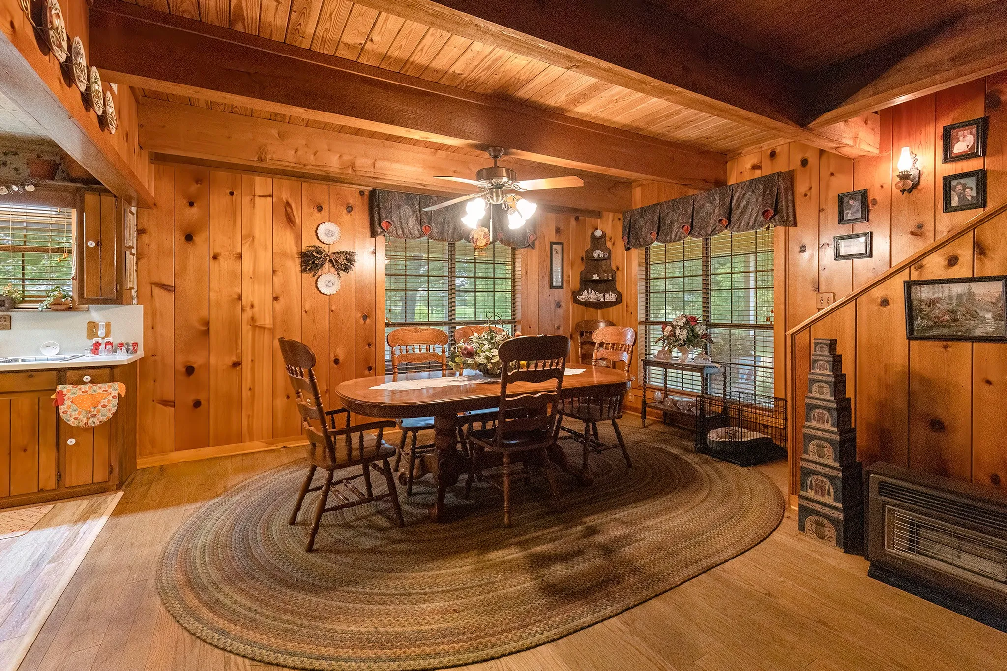 Dining room with light wood-style flooring, wood walls, ceiling fan, and a wood ceiling with exposed beams