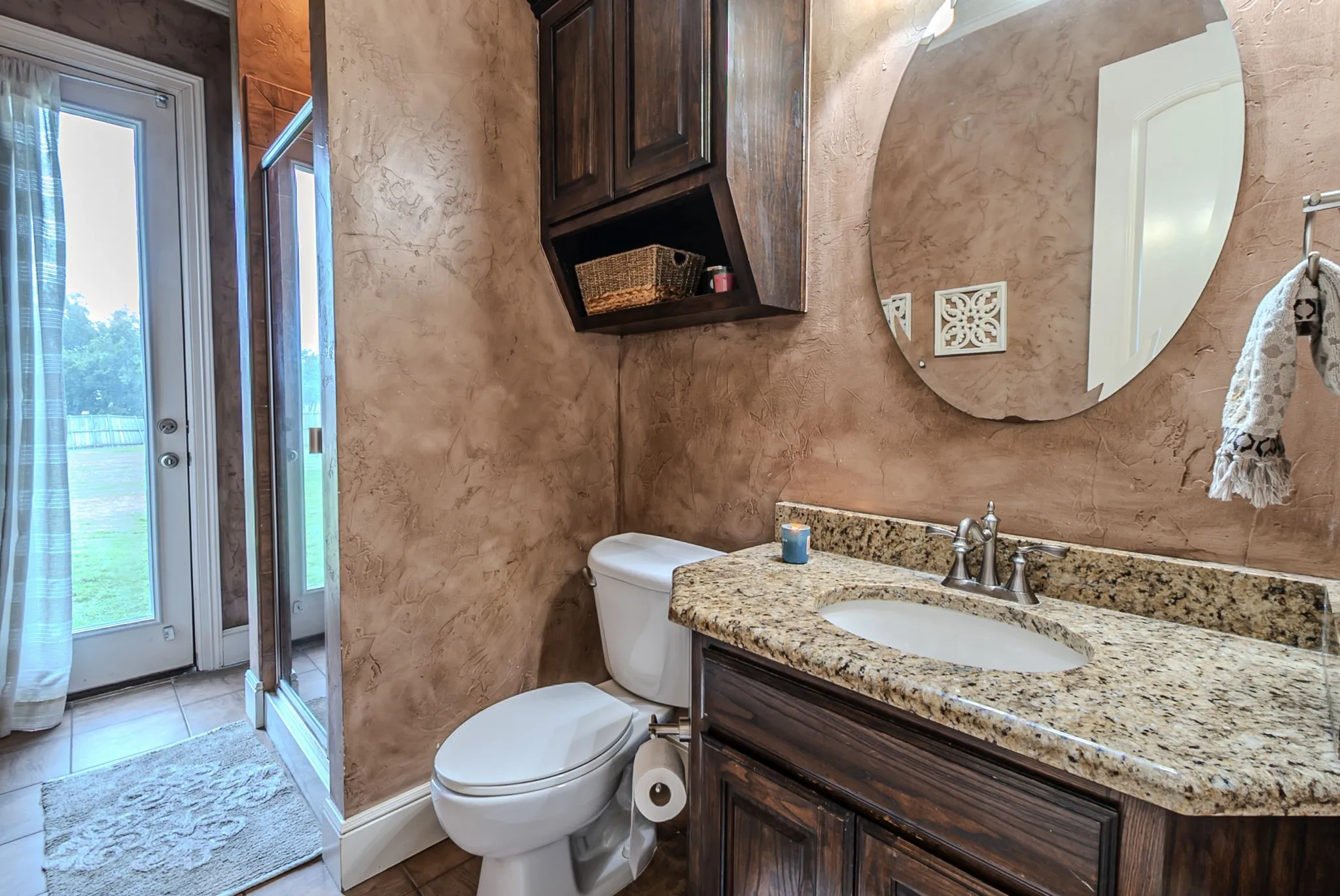 Downstairs guest bathroom with granite countertops, decorative painted walls, spacious shower, and door to exterior - perfect for a pool bathroom!