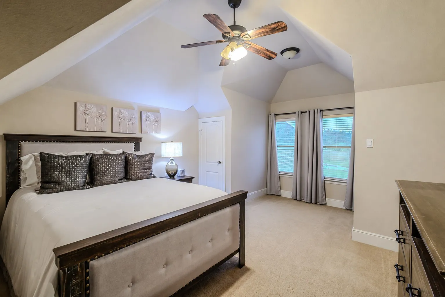 Upstairs bedroom with ceiling fan and large windows.