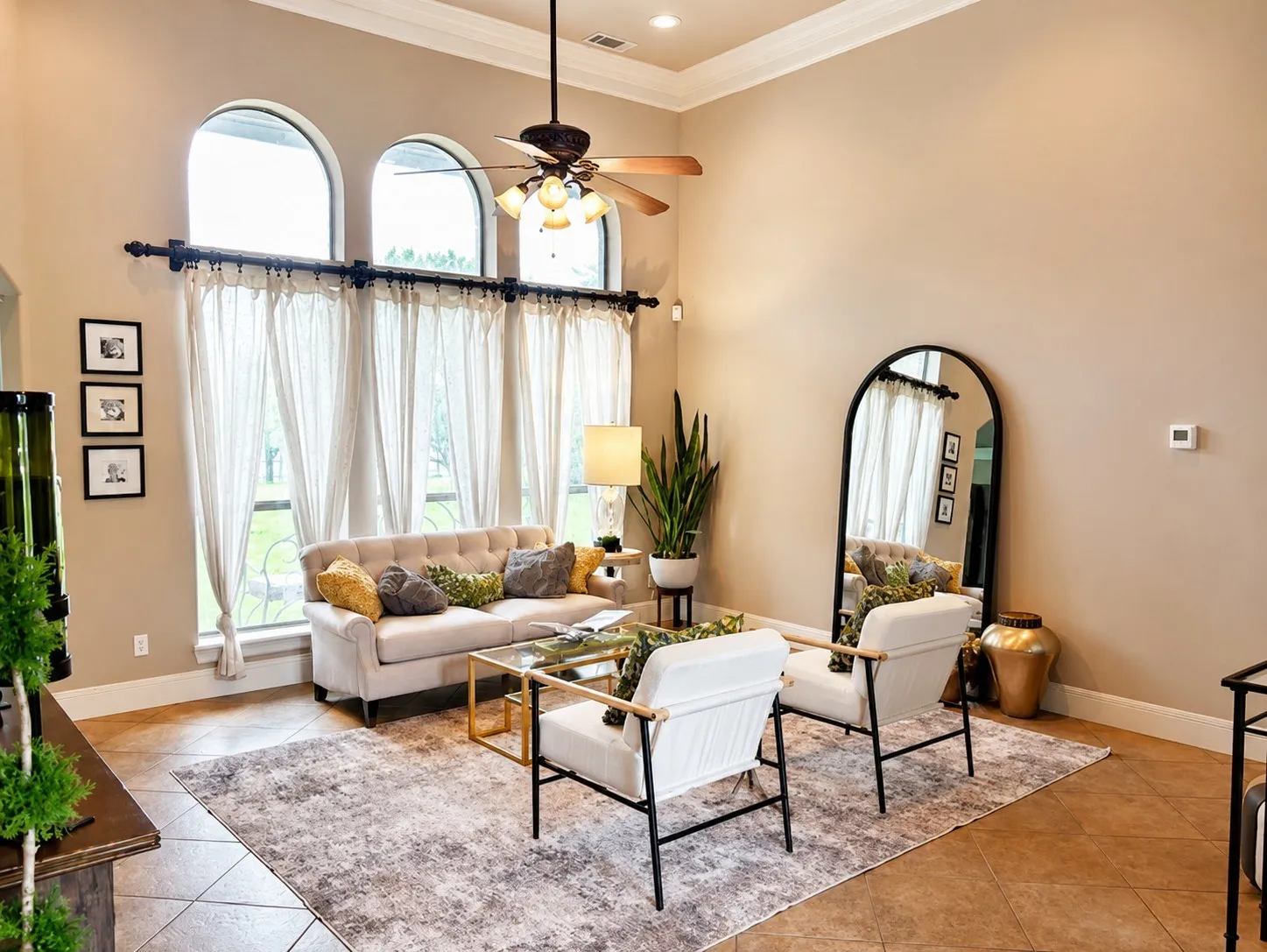 Another view of the living room facing the windows featuring natural light, crown molding, ceiling fan and tons of space!