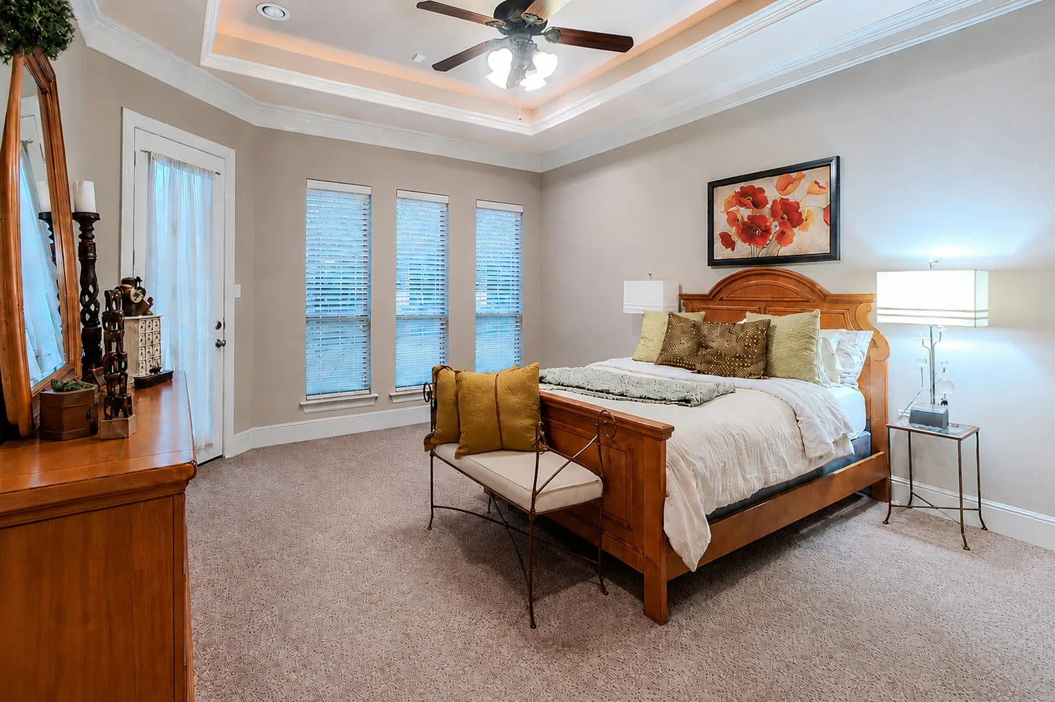 Spacious primary bedroom with tray ceiling, large windows, and exterior door to the back yard.