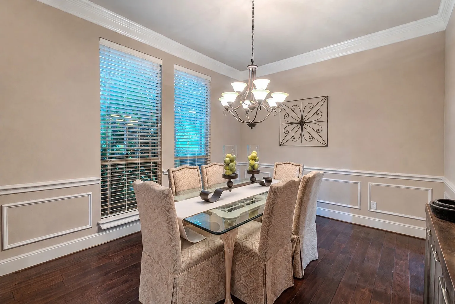 Formal dining room featuring wood flooring, decorative wainscoting, and natural light.