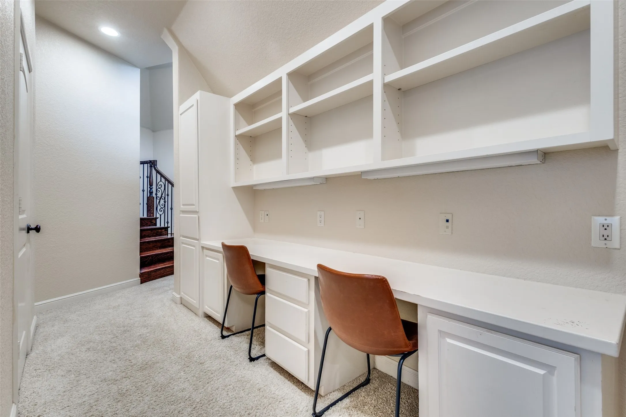 Unfurnished office featuring built in desk and light carpet