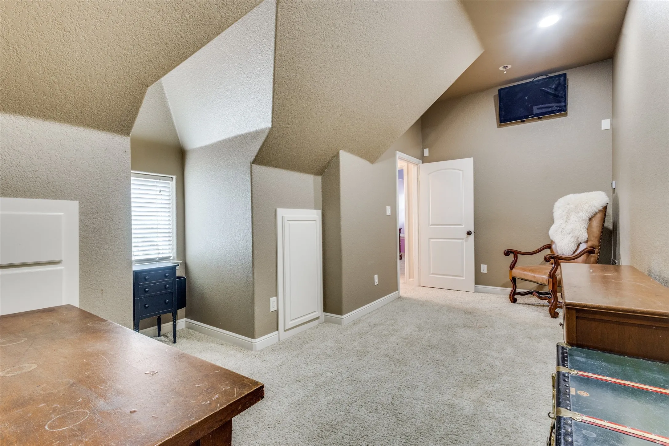 Living area with light colored carpet, a textured wall, and a textured ceiling