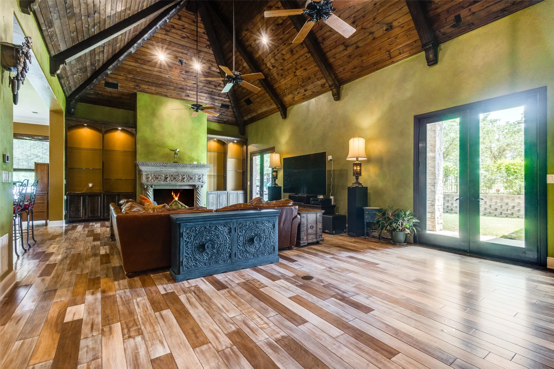 Living room featuring high vaulted ceiling, a wood ceiling with exposed beams, a warm lit fireplace, hardwood / wood-style flooring, and plenty of natural light
