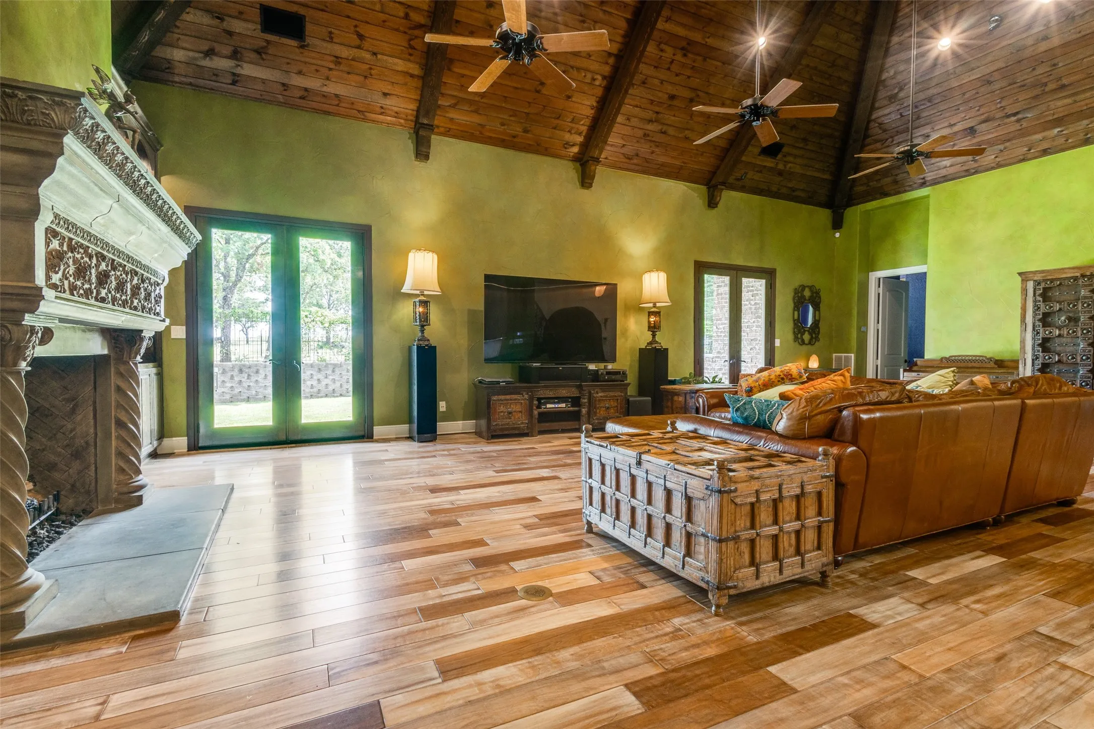 Living area with high vaulted ceiling, a wood ceiling with exposed beams, a fireplace with raised hearth, french doors, and light wood-type flooring